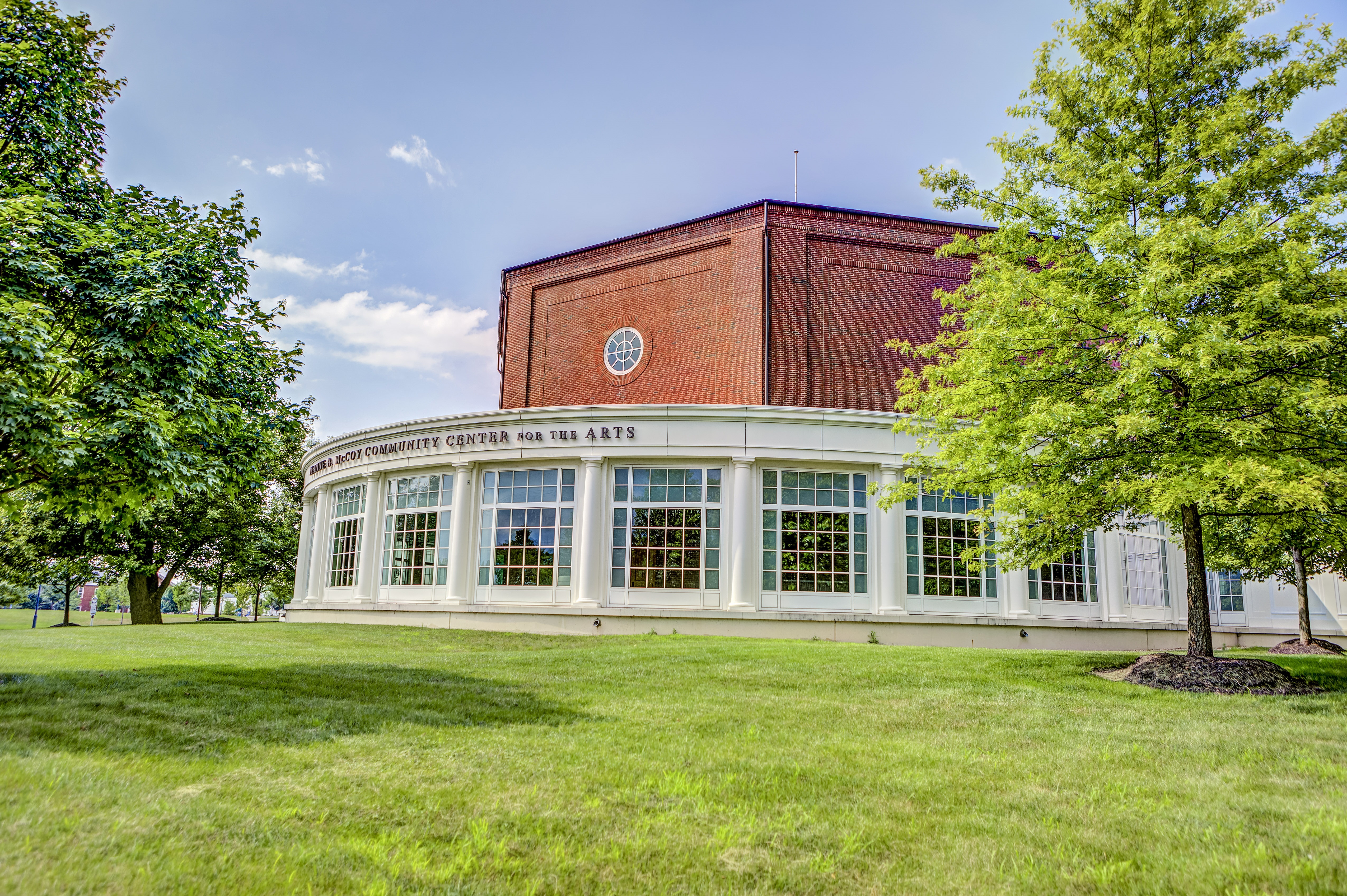 Exterior of a brick performing arts center with a curved glass-and-white lobby facade.