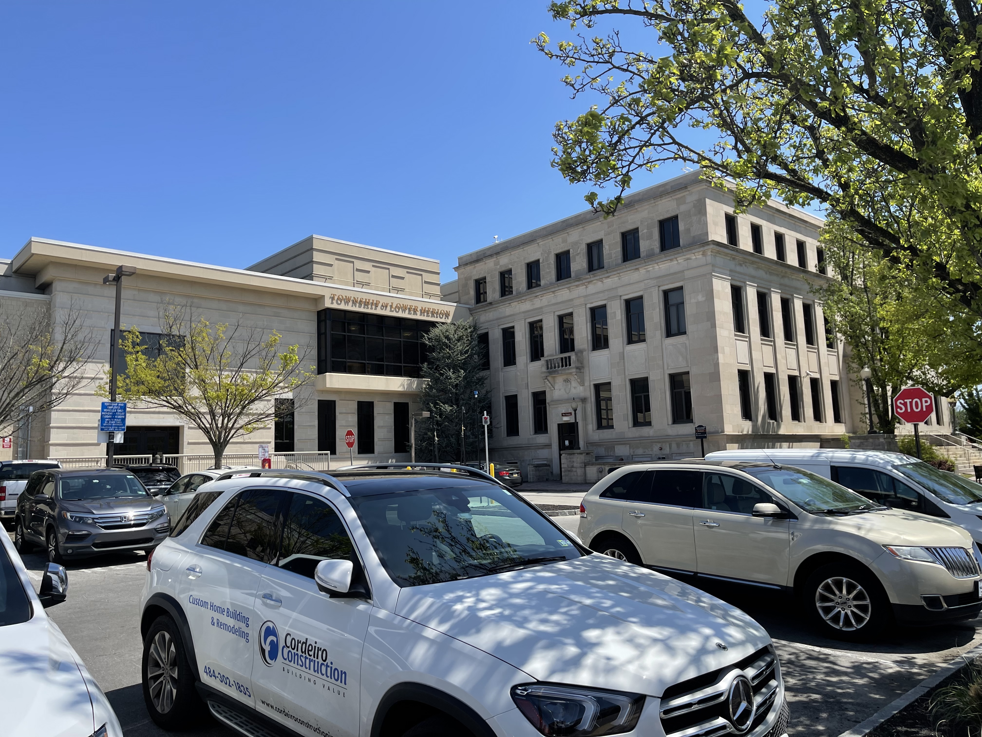 Stone government building with parked cars under a clear blue sky.