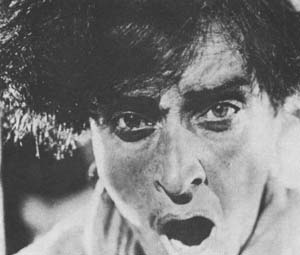 Black-and-white close-up of a man's face with an intense, anguished expression.