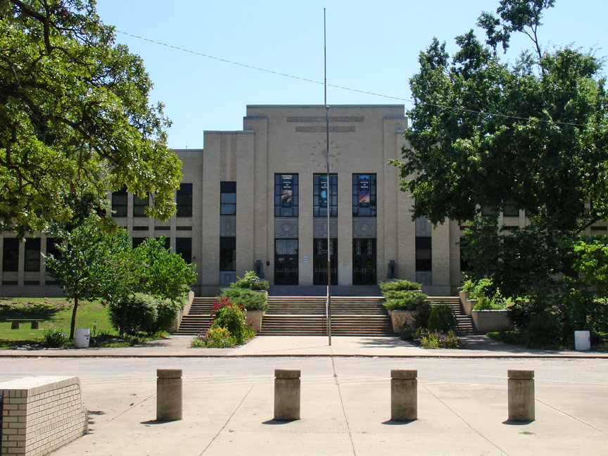 Multi-story Art Deco school building with a flagpole and steps at the main entrance.