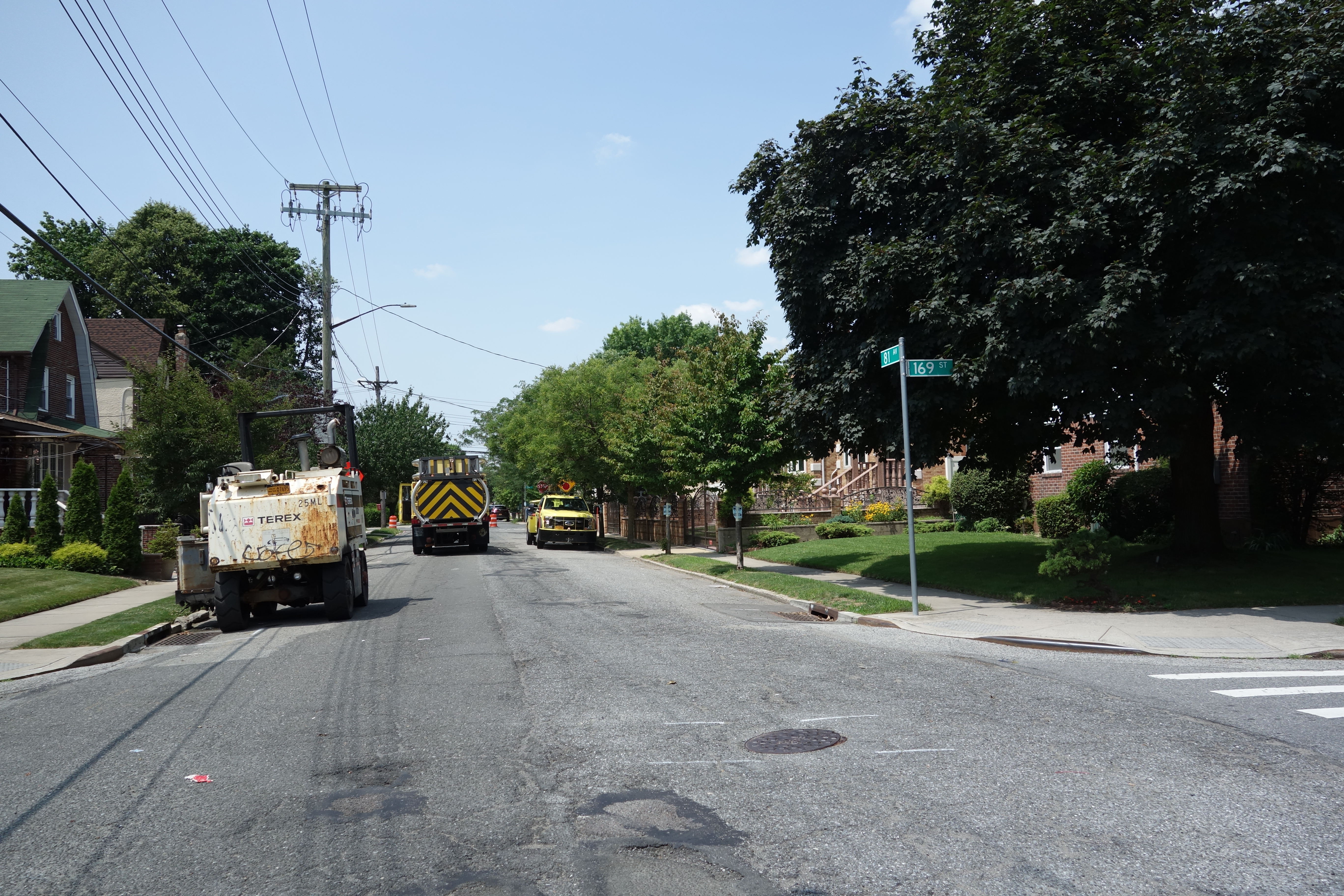 Paving machine and truck resurfacing a residential street intersection.