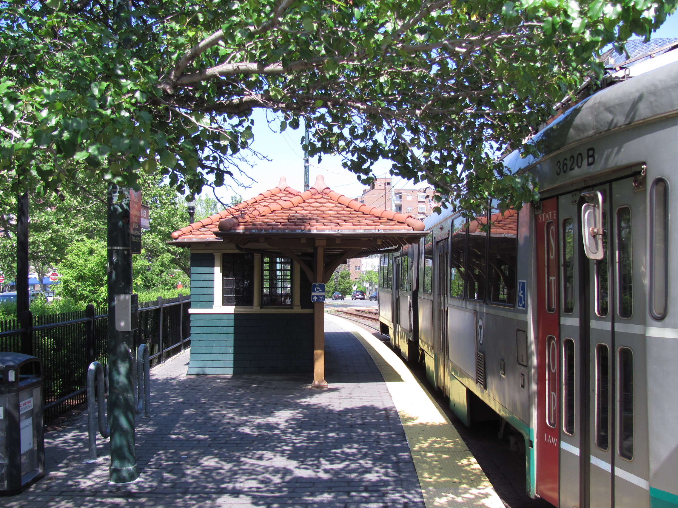Train stopped at Coolidge Corner MBTA station beside a small historic shelter building.