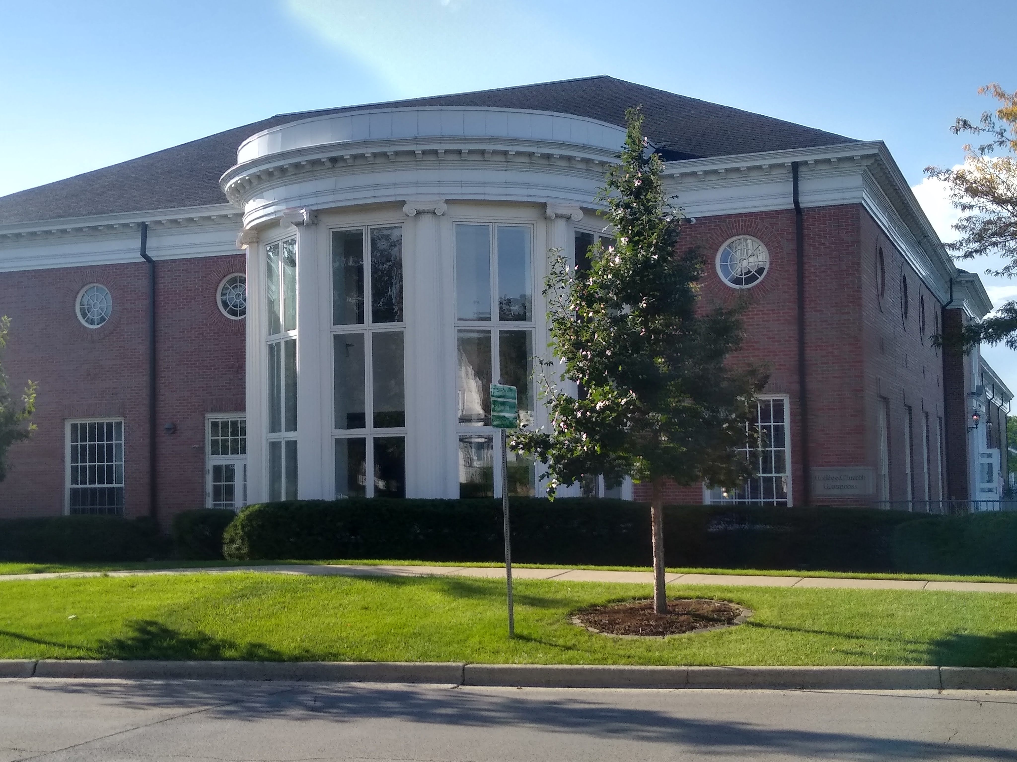 Large red-brick church building with white neoclassical columns and a green front lawn.