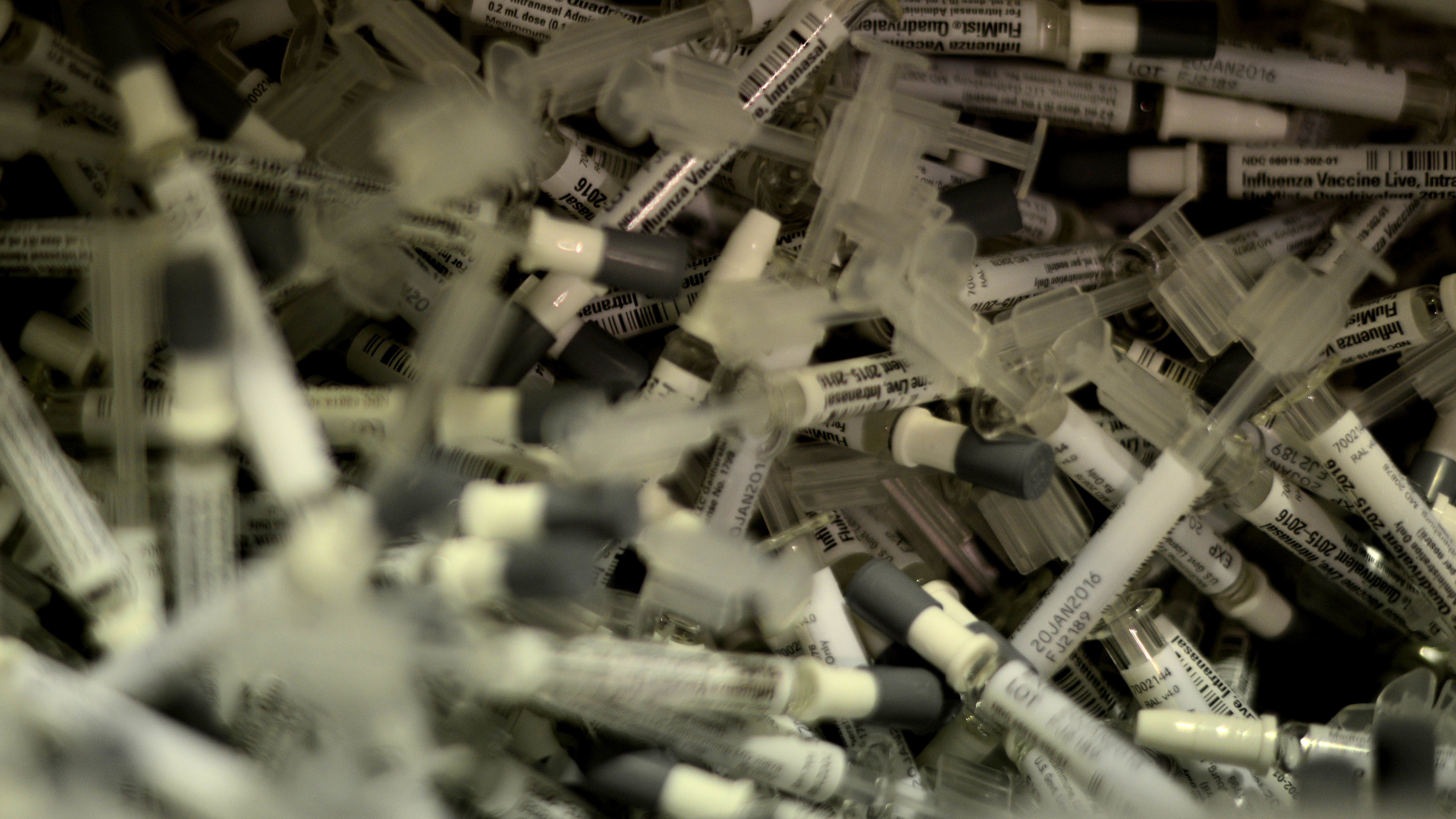A pile of flu vaccine syringes and nasal spray applicators labeled influenza vaccine.