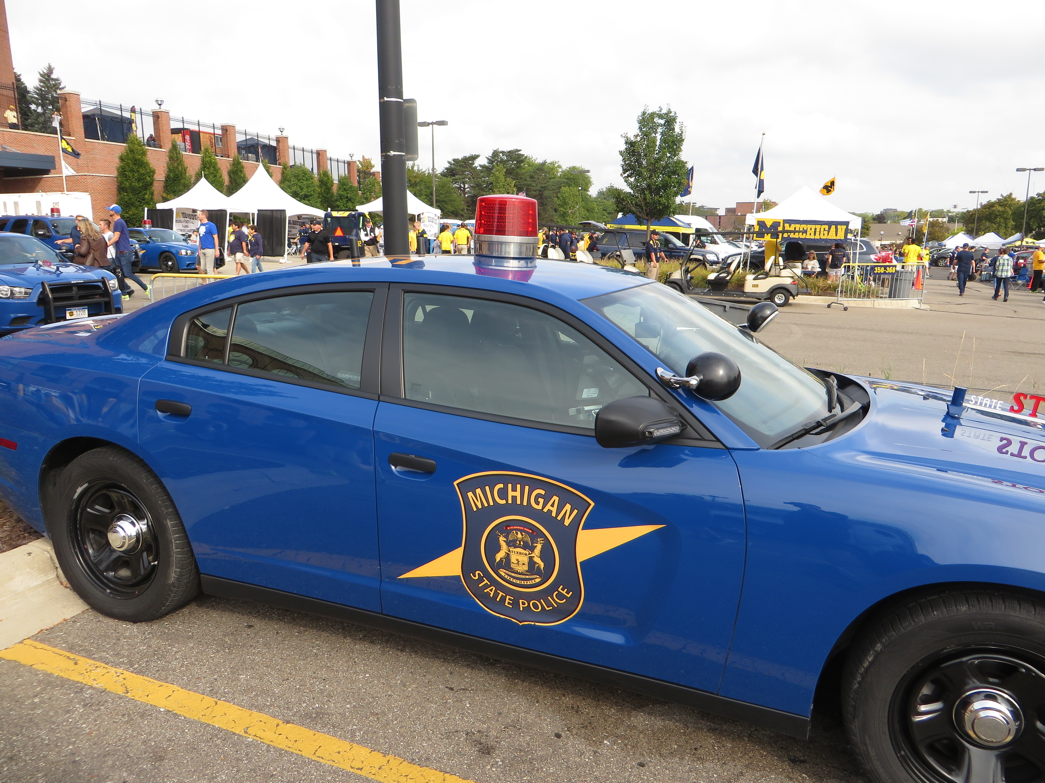 Blue Michigan State Police Dodge Charger patrol car with roof light bar parked outdoors.