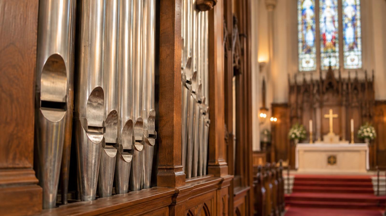 Large pipe organ with gleaming metal pipes inside a church sanctuary.