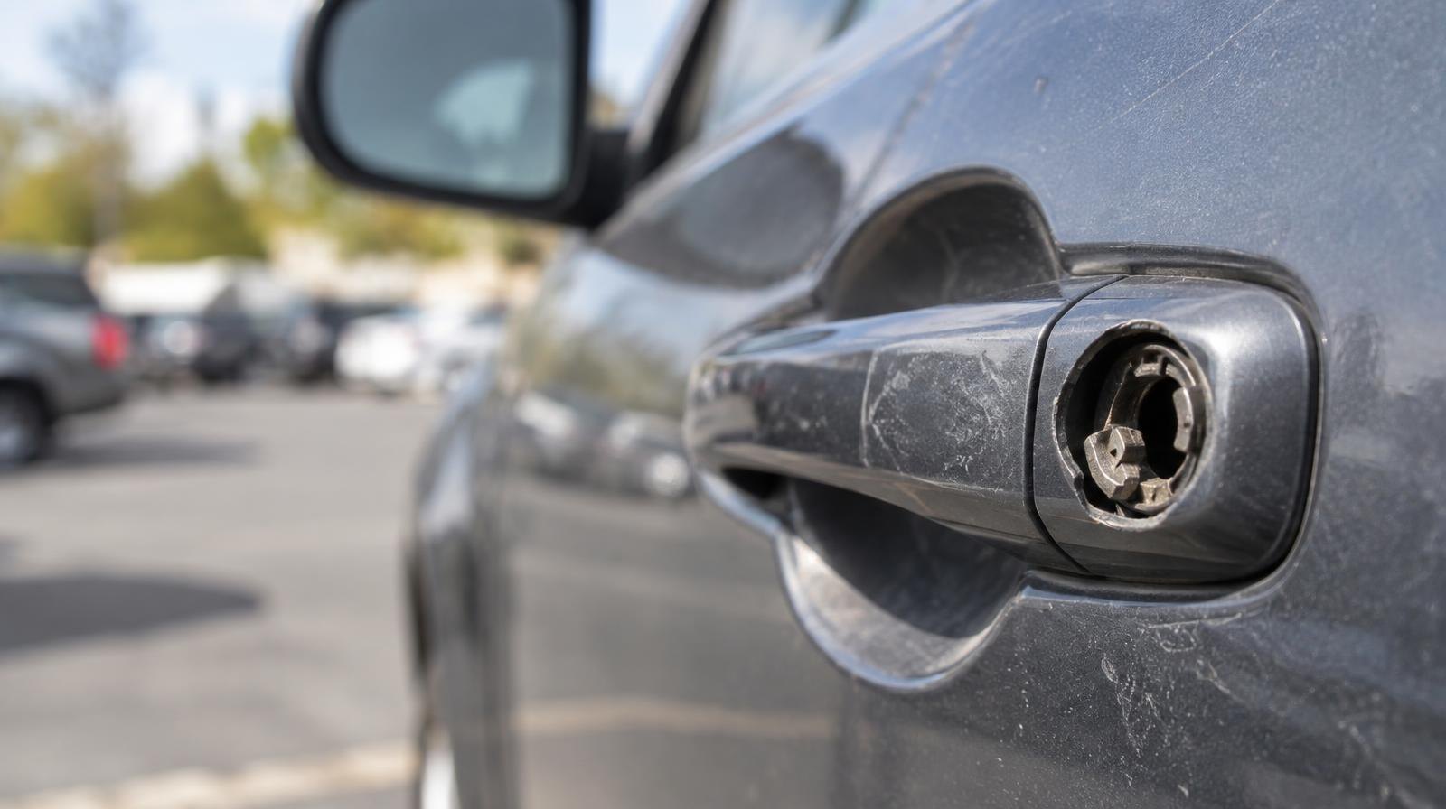 Close-up of a car door handle with a broken lock mechanism.