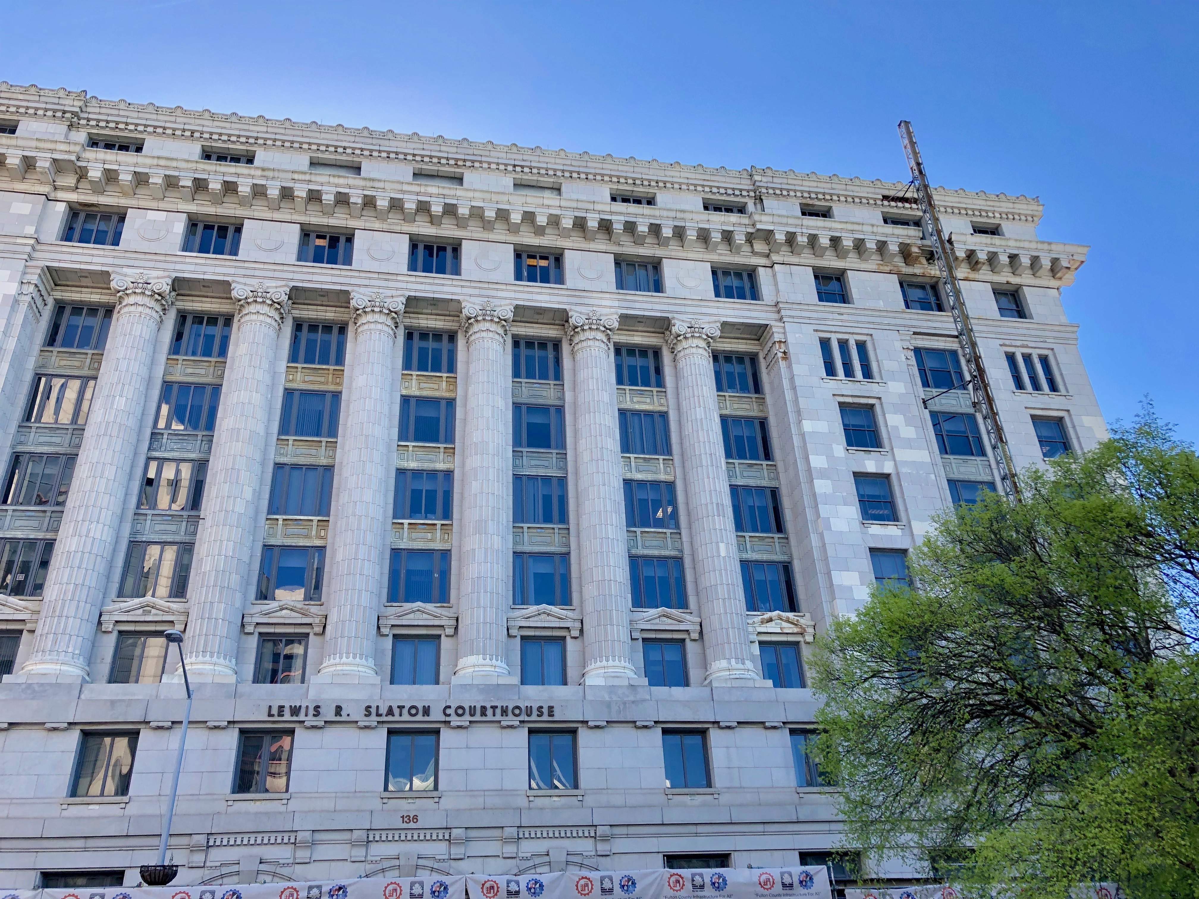 Neoclassical stone courthouse with tall columns under a clear blue sky.