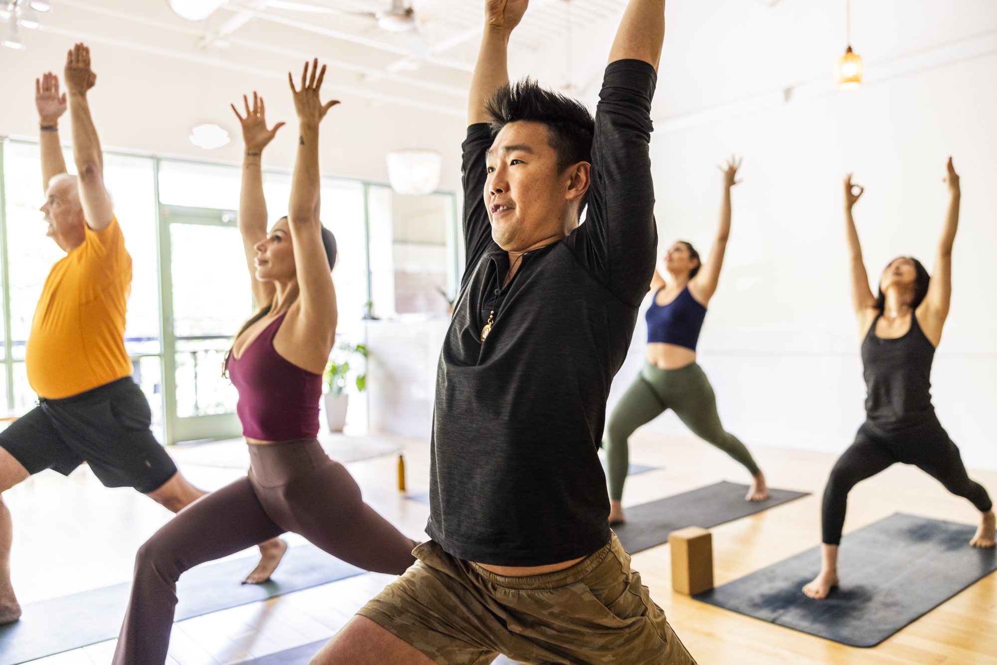 Diverse group of students doing crescent lunge pose during yoga class