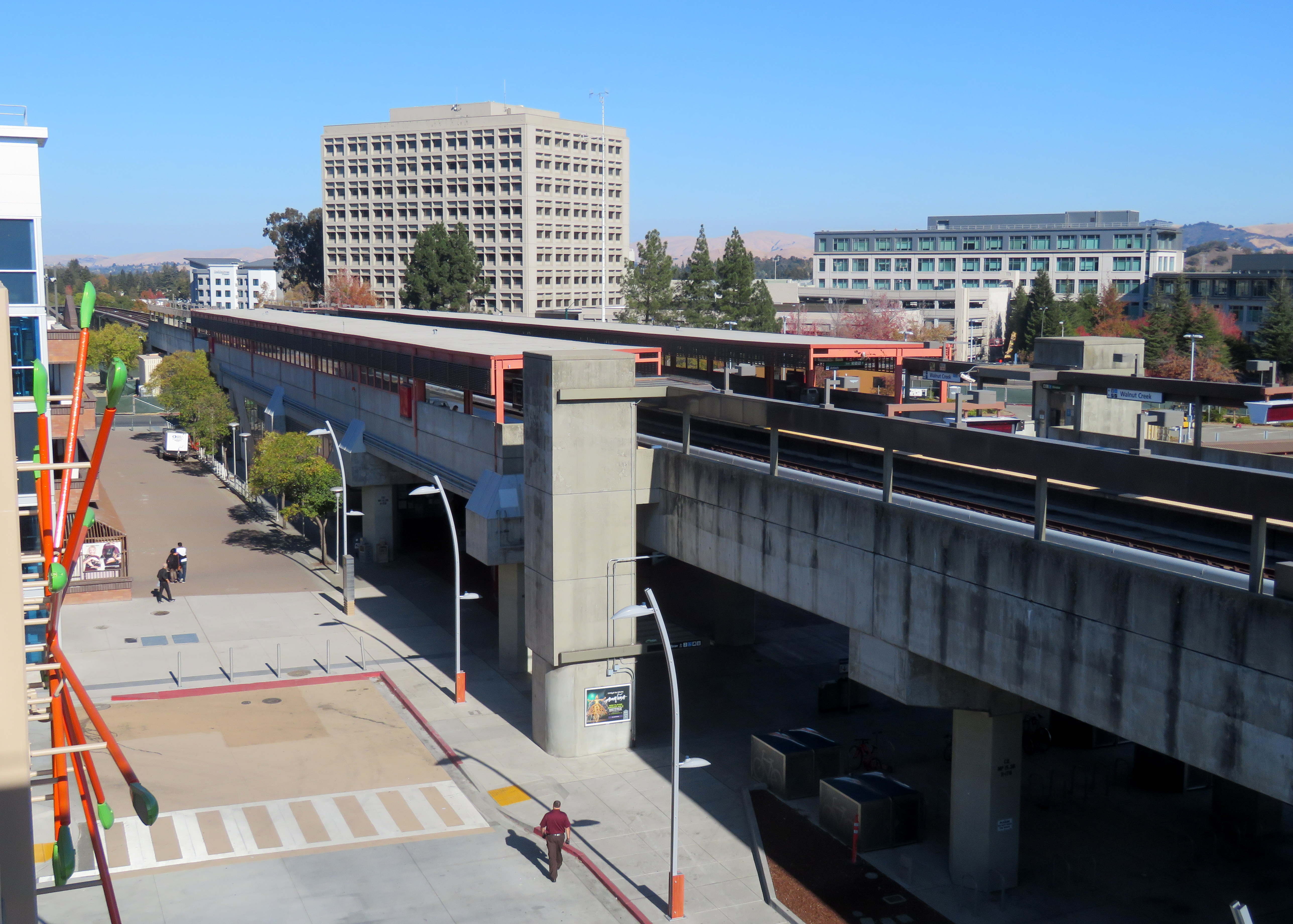 Elevated BART station structure with surrounding streets and office buildings under blue sky.