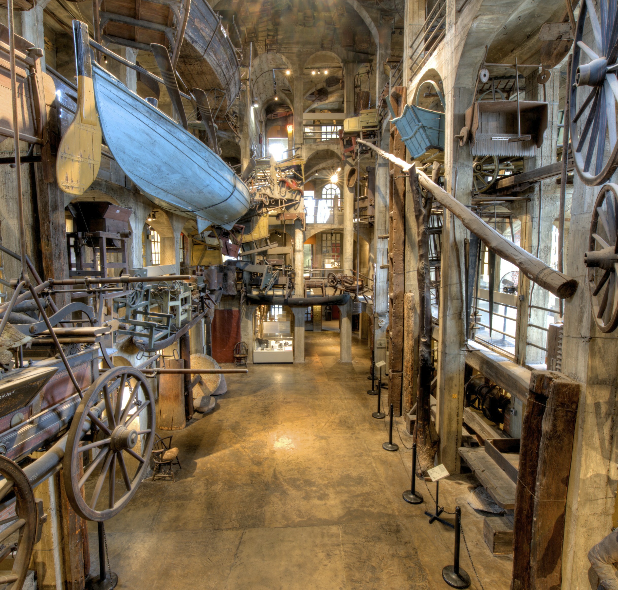Multi-story museum atrium with a whale boat and wagon wheels suspended from upper levels.