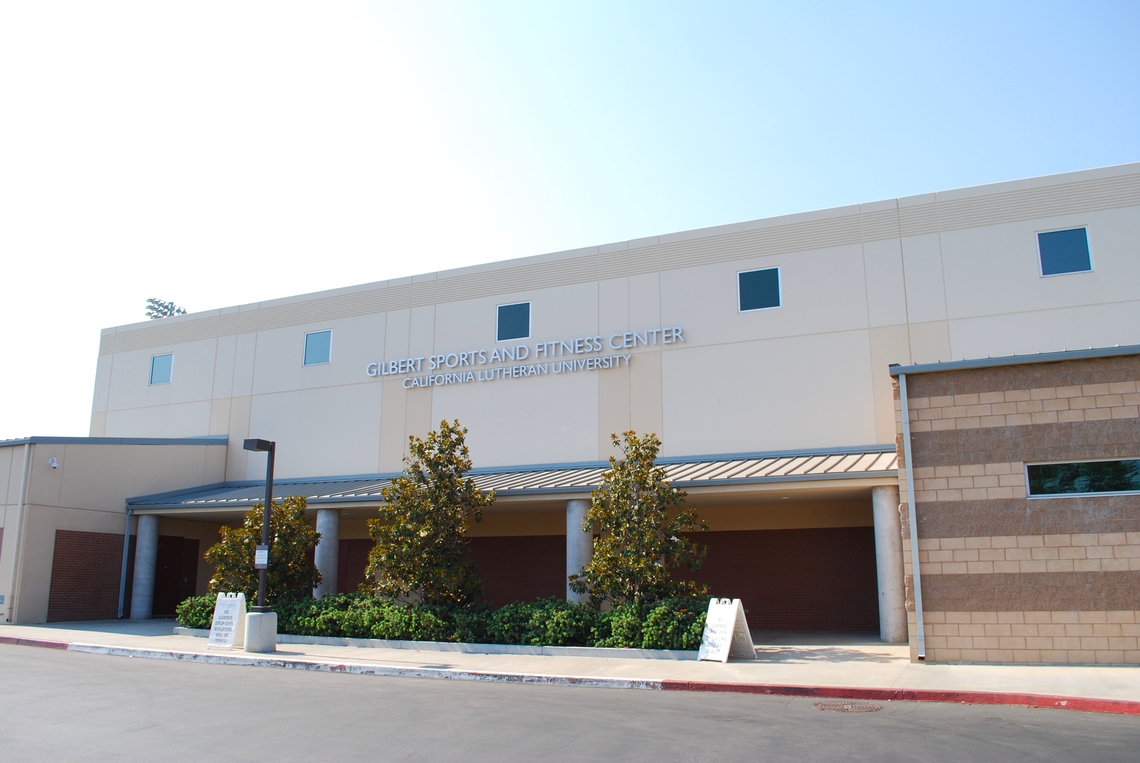 Exterior of a sports center building with blue accents and brown roll-up doors.