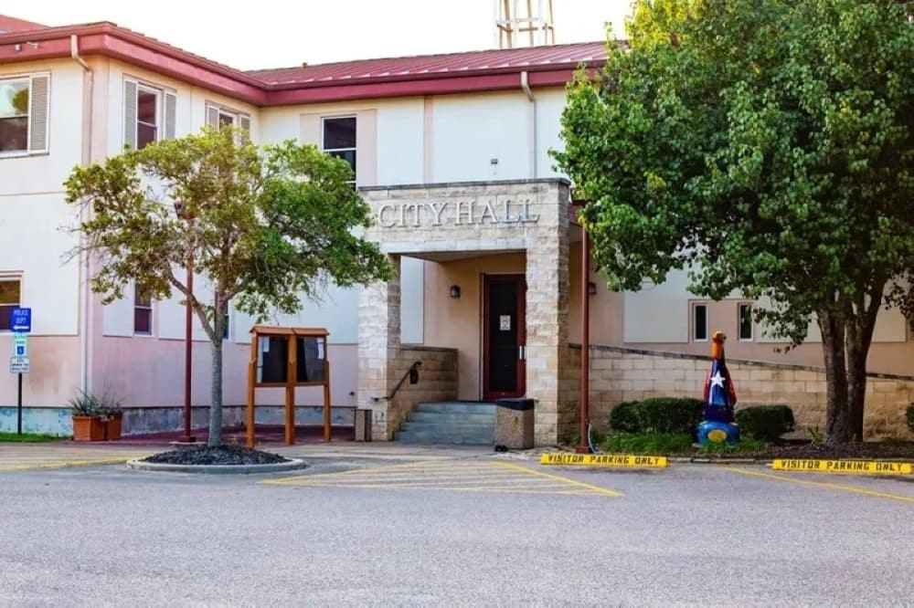 Exterior of a stone-facade city hall building with steps leading to the entrance.