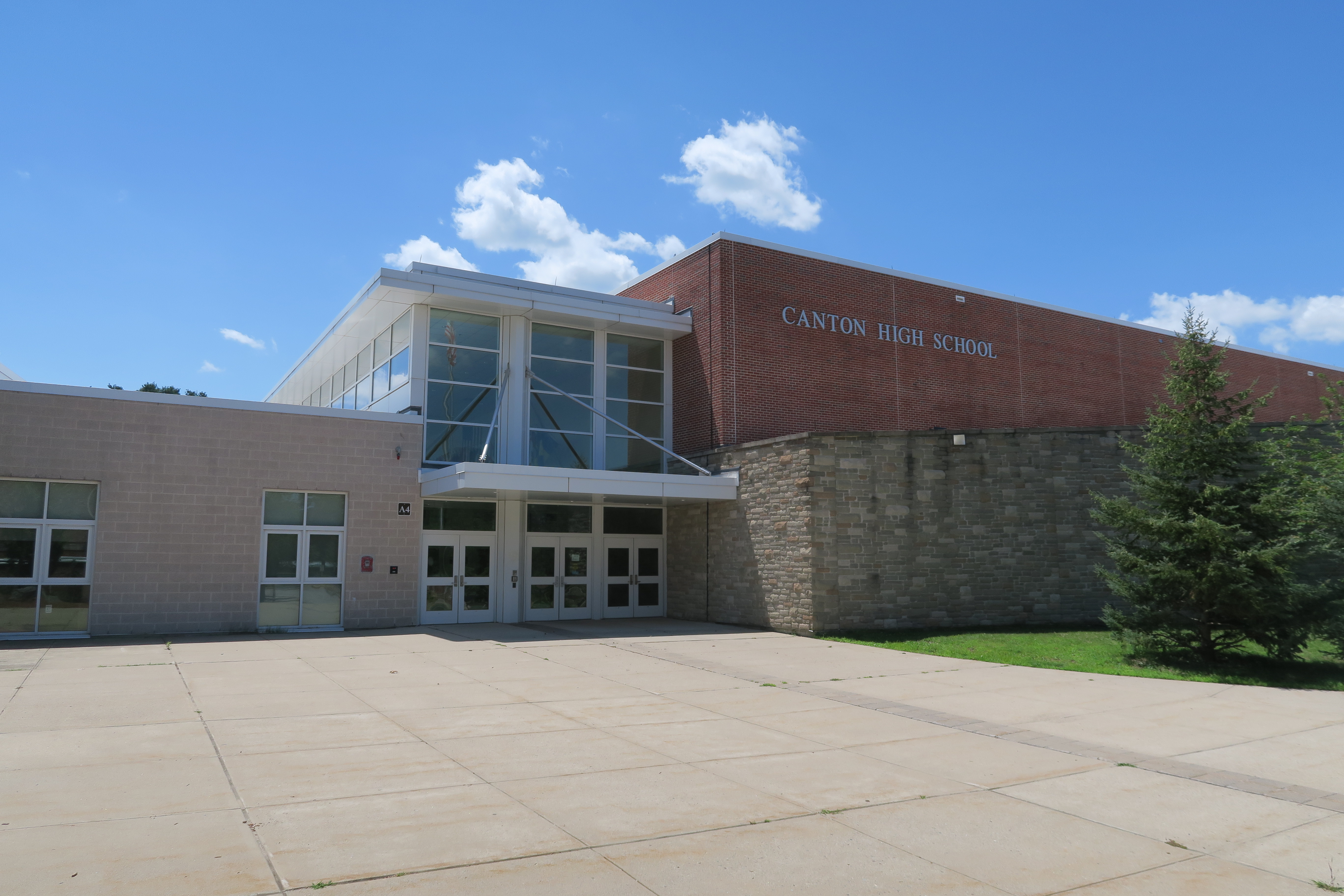 Brick school building with large glass entrance doors and a sign reading Canton High School.