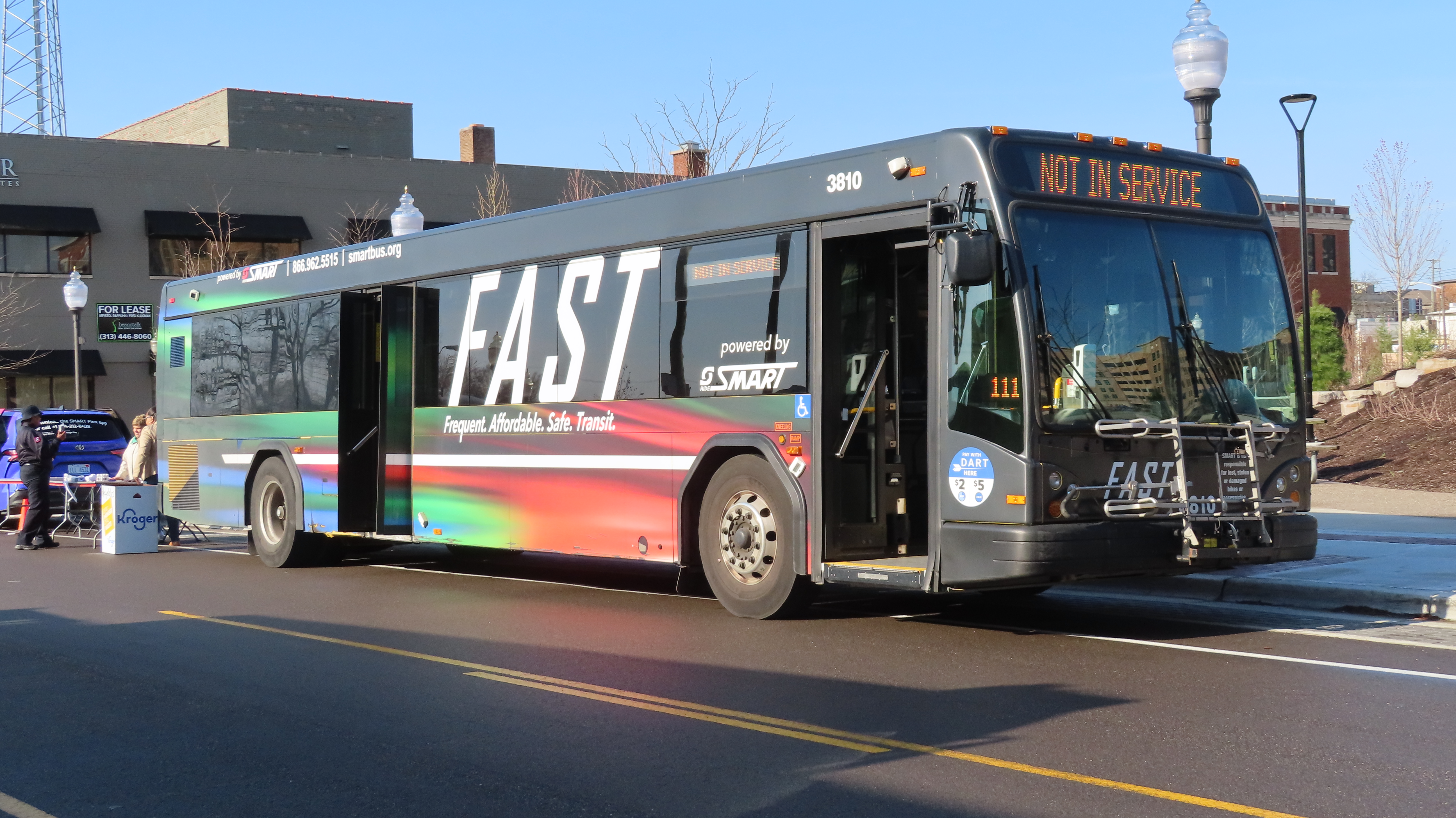 A SMART bus in colorful rainbow-striped FAST livery parked on a city street.