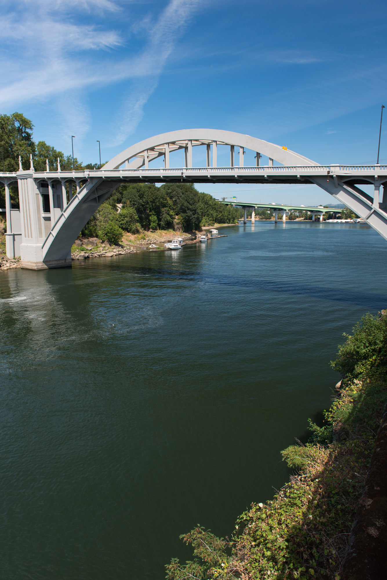 White concrete arch bridge over the Willamette River between two Oregon cities.