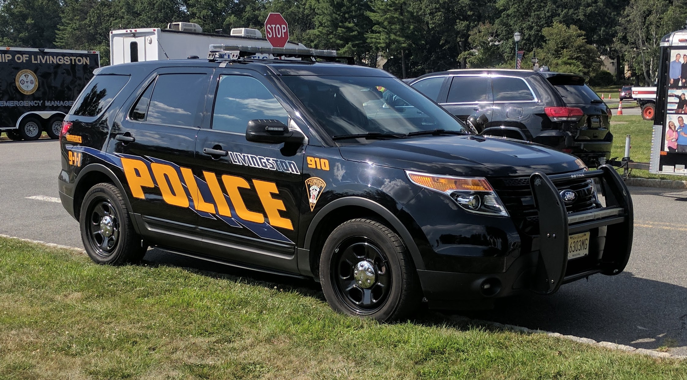 Black and gold Livingston Police Ford SUV parked on grass with emergency management vehicle behind it.