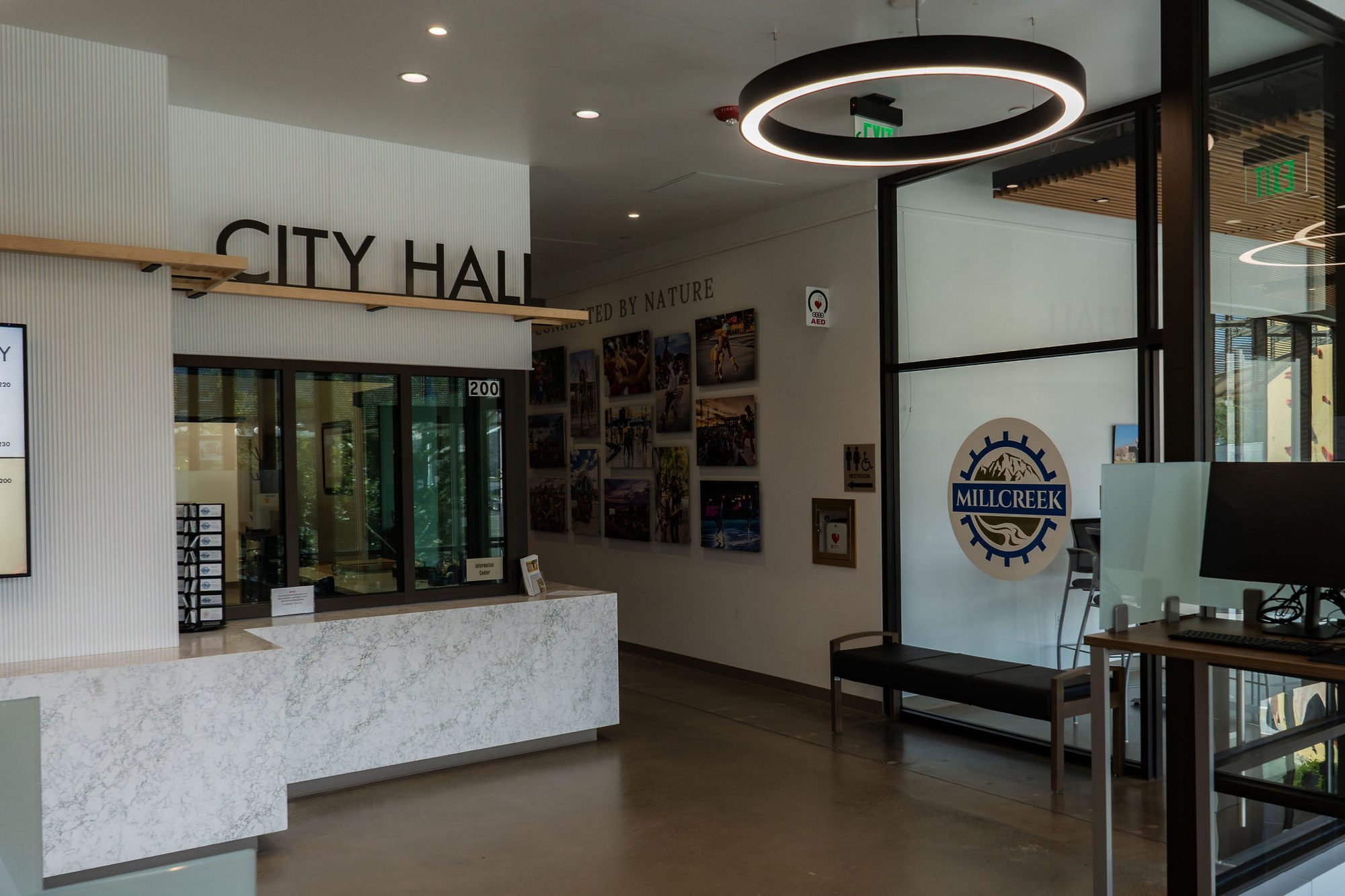 Interior lobby of a city hall with a marble reception desk and city seal on the wall.