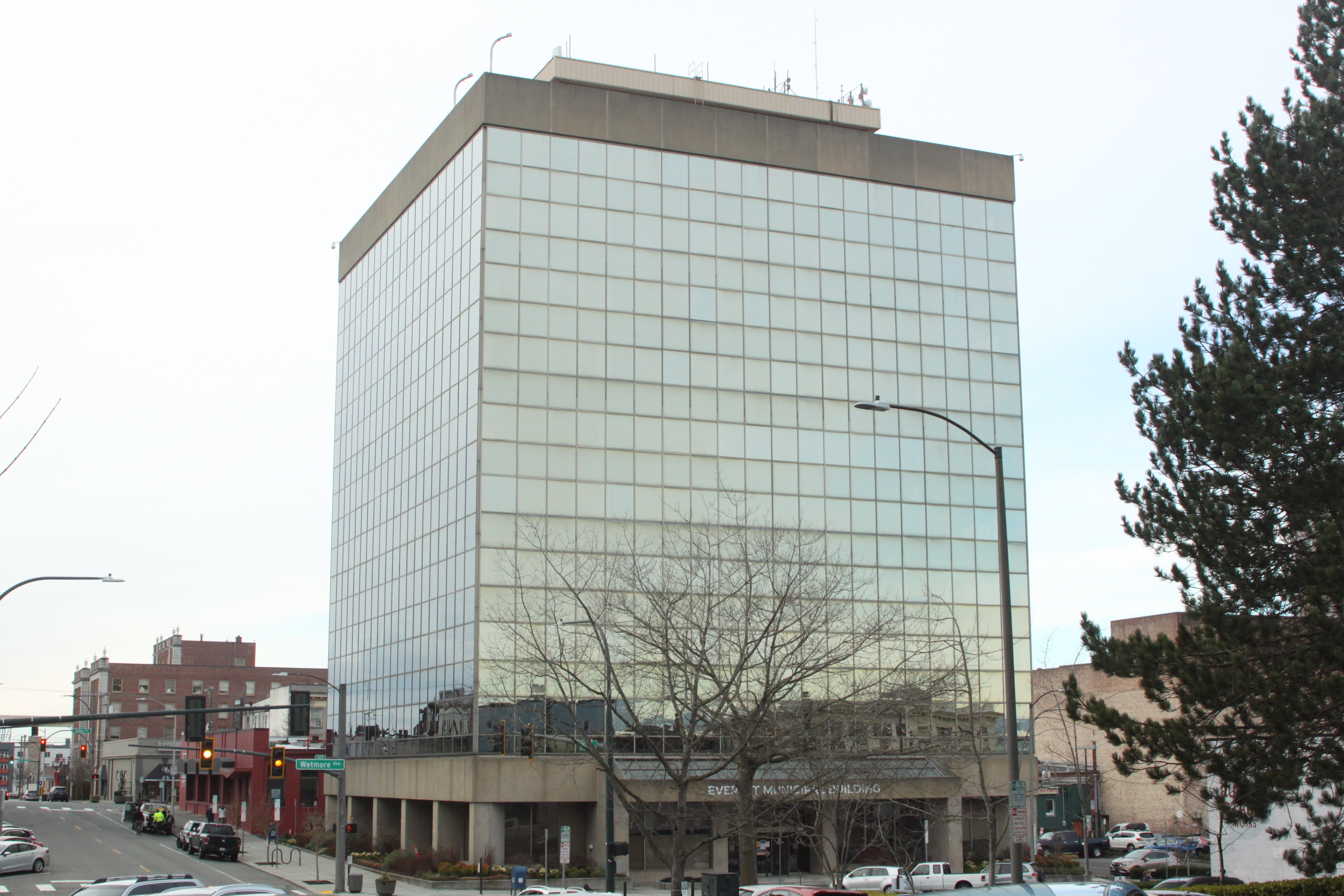 Tall glass-curtain-wall government office tower on a city street.