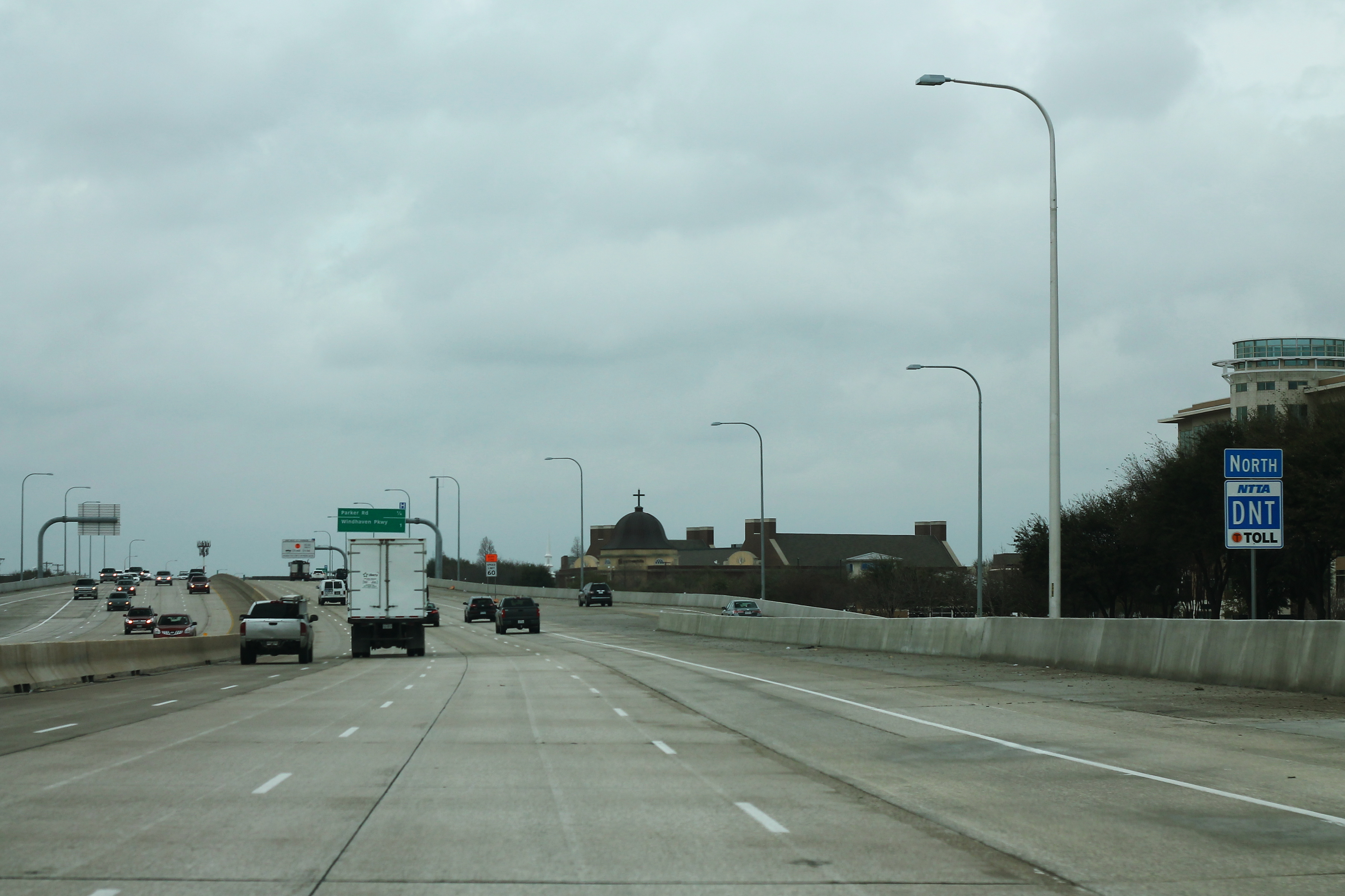 Multi-lane tollway with blue North DNT Toll sign and street lights.