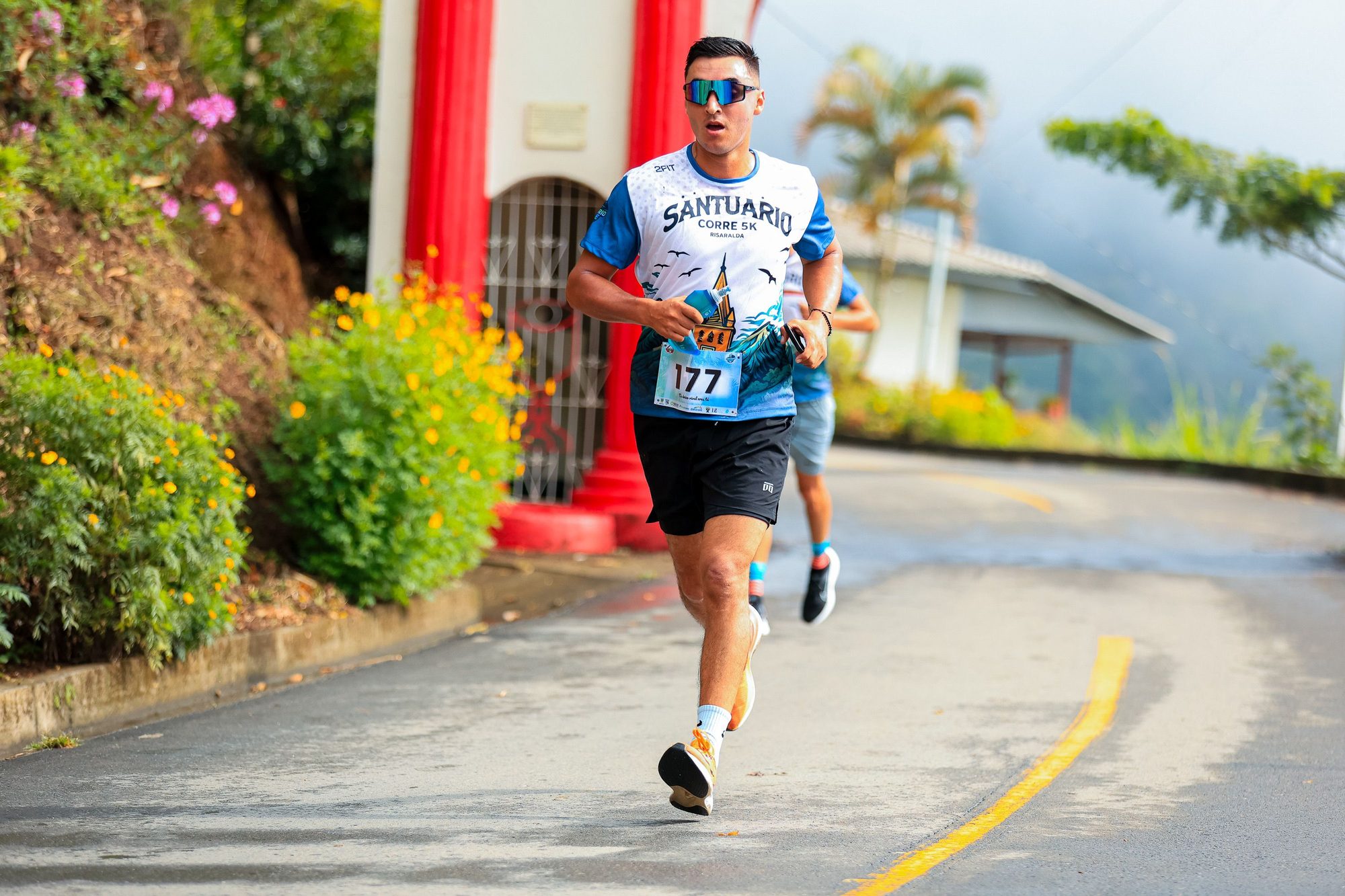 Man running in a vibrant outdoor 5K race, showcasing athletic dedication and lively environment.