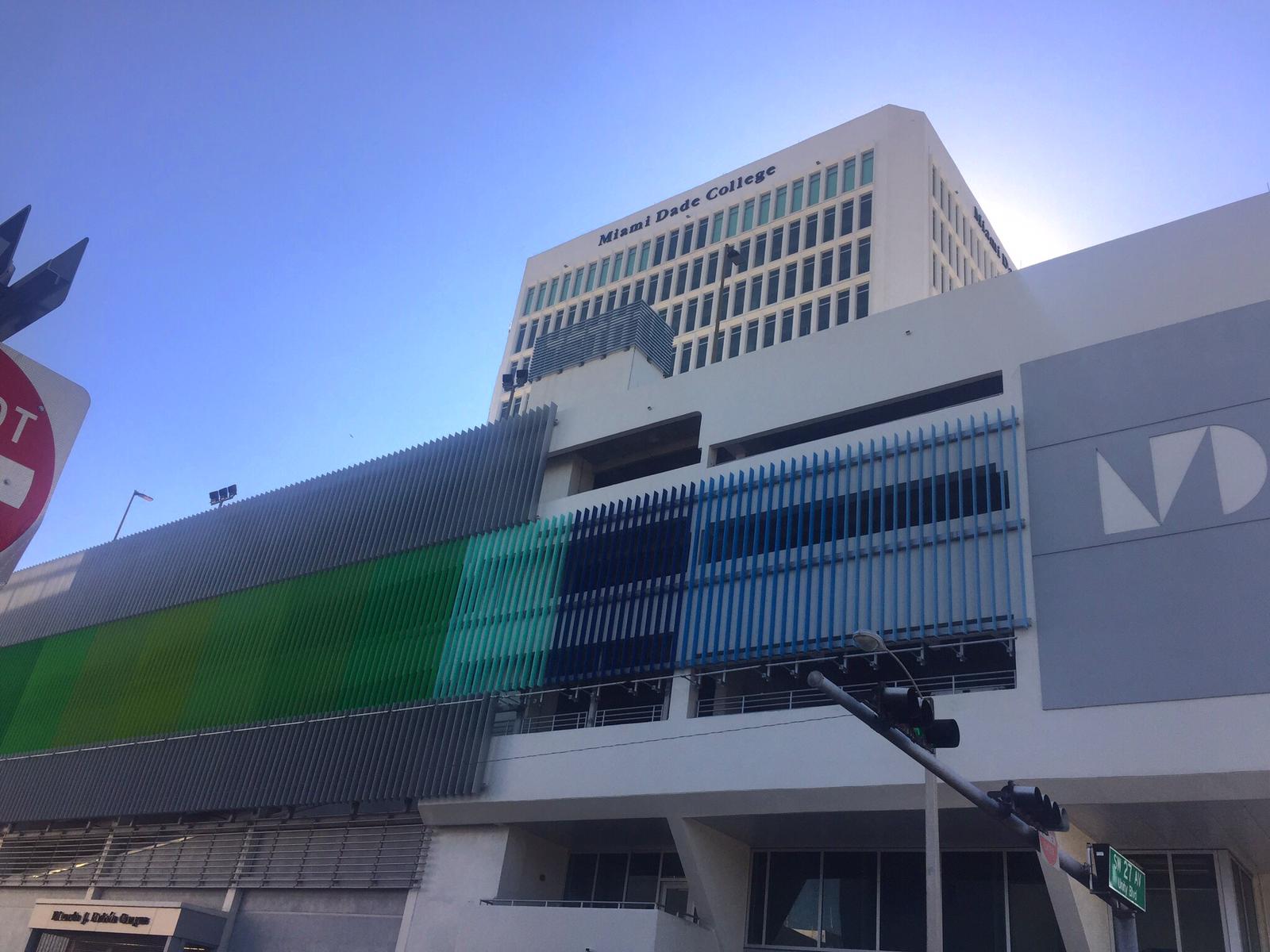 College building with green and teal facade panels and Miami Dade College signage on a sunny day.