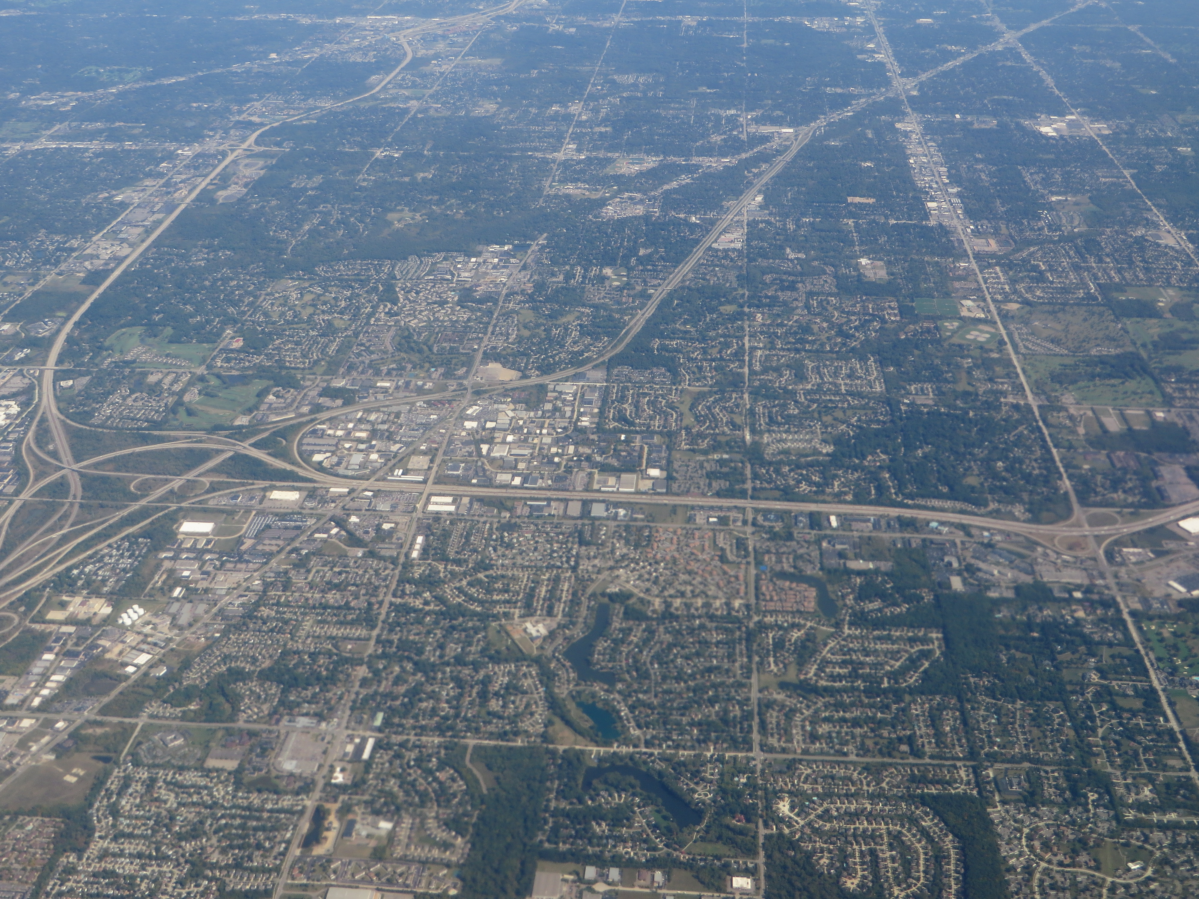 Aerial view of a suburban city with streets, neighborhoods, and highway interchanges.