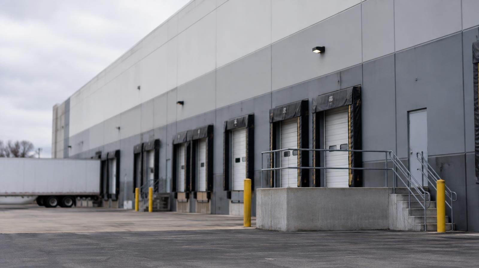 Large industrial warehouse exterior with flat roof and loading dock doors.