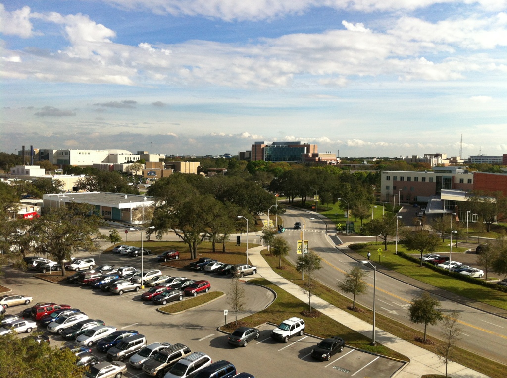 Aerial view of a university campus with parking lots, roads, and buildings.