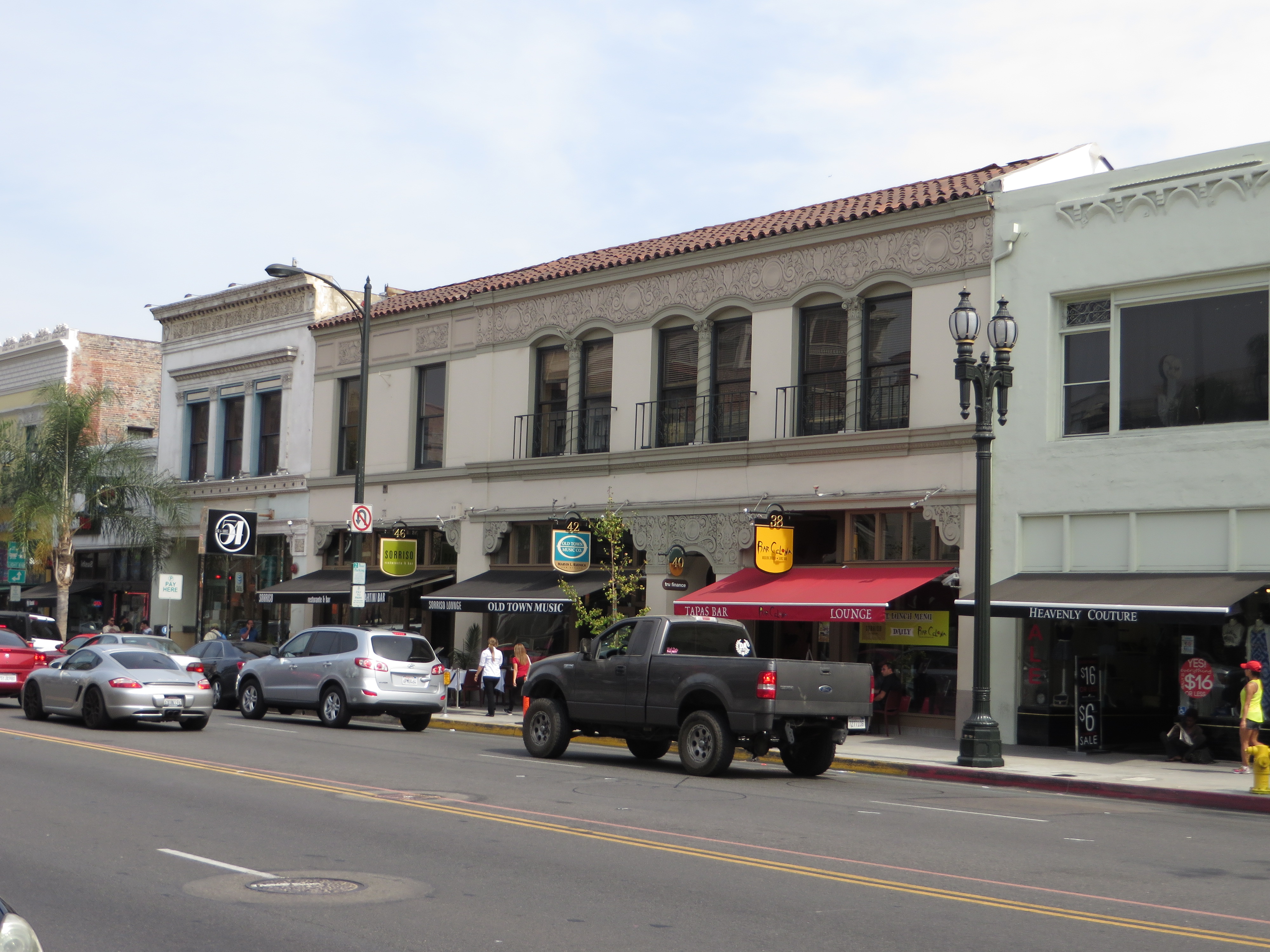 Historic storefronts with awnings line a busy commercial street on a sunny day.