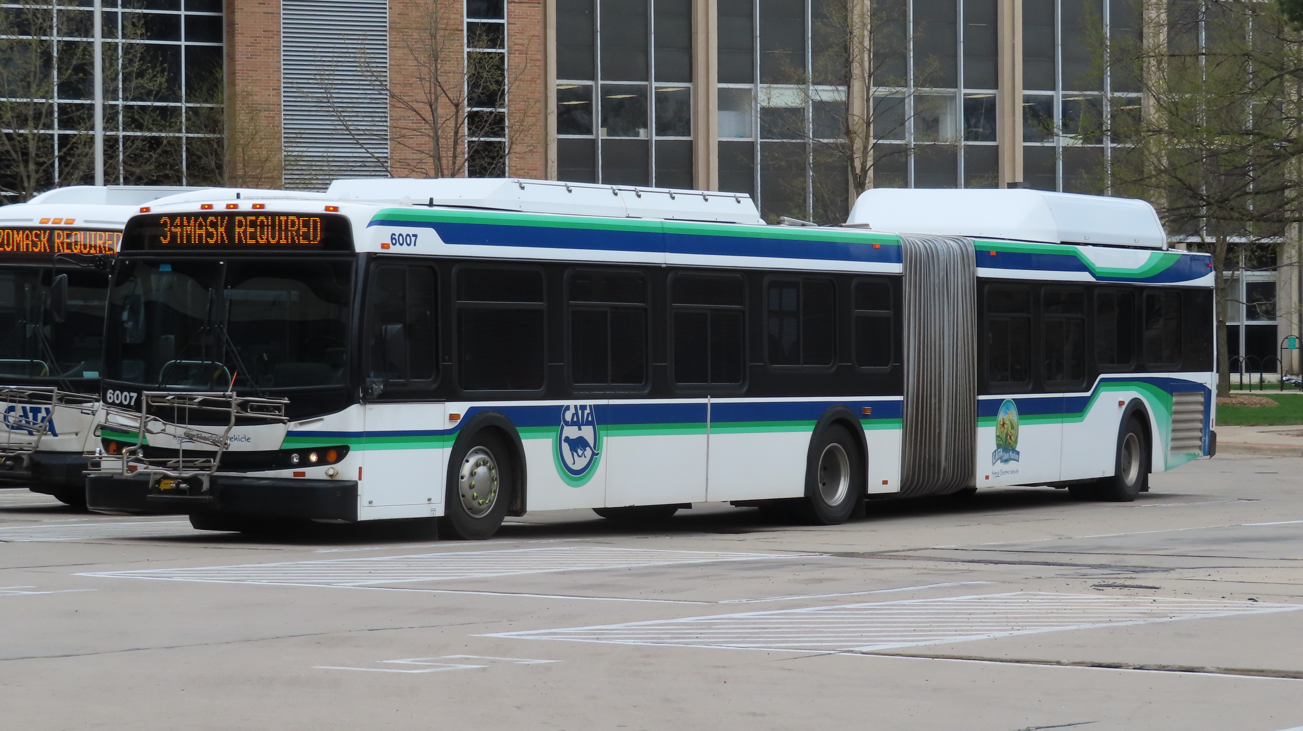 A white articulated CATA bus with green and teal striping parked at a transit center.