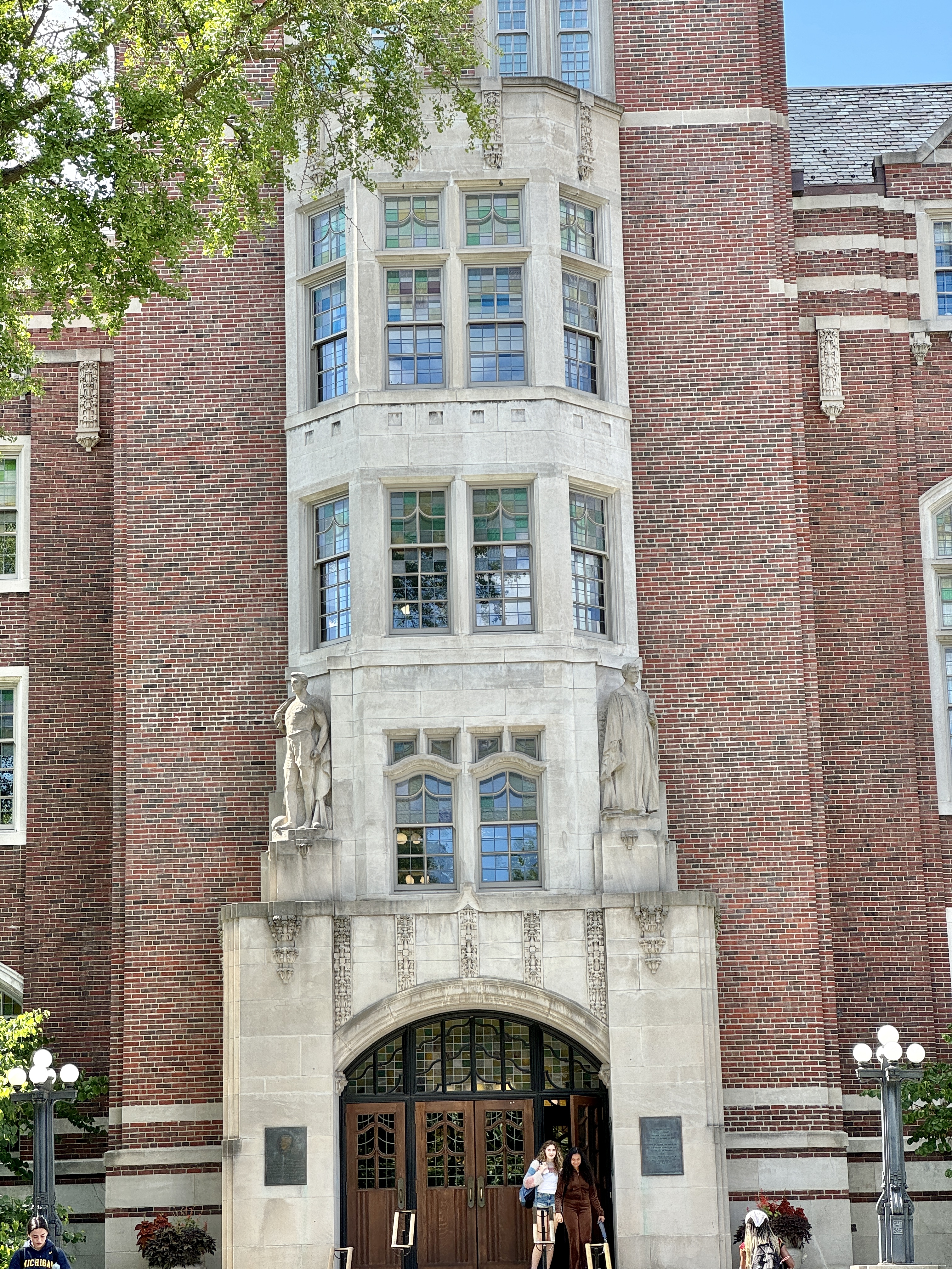 Close-up of a red brick Gothic Revival building entrance with limestone trim and an arched doorway.