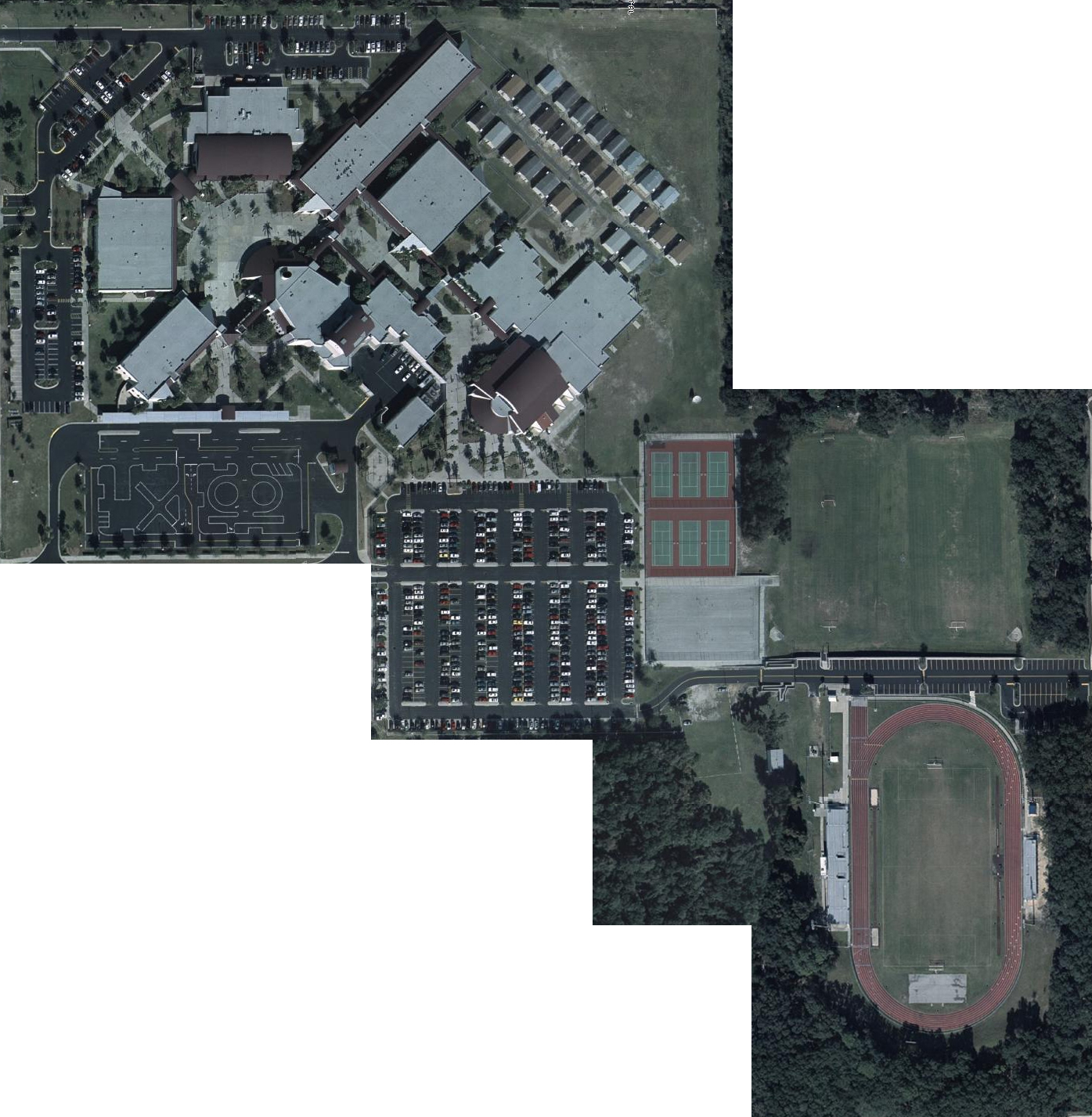 Aerial view of a large school campus with buildings, parking lots, a red athletic track, and tennis courts