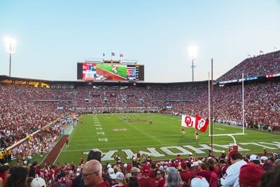 Packed college football stadium filled with fans in red, viewed from the end zone.