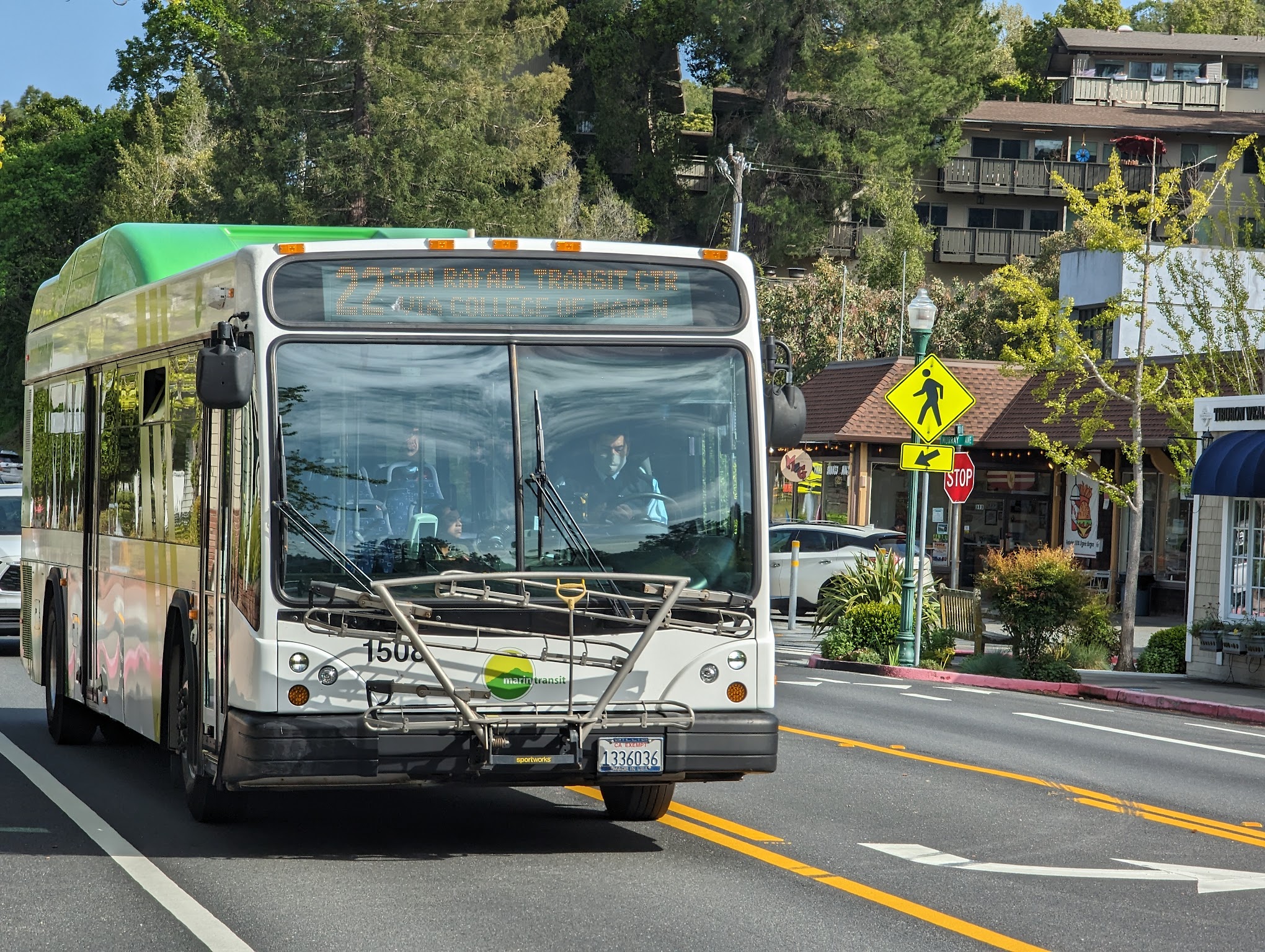 Green and white Marin Transit bus with a front bike rack traveling on a street.