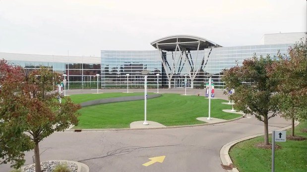 Modern glass-and-steel institutional building with an arched canopy entrance and flagpoles.