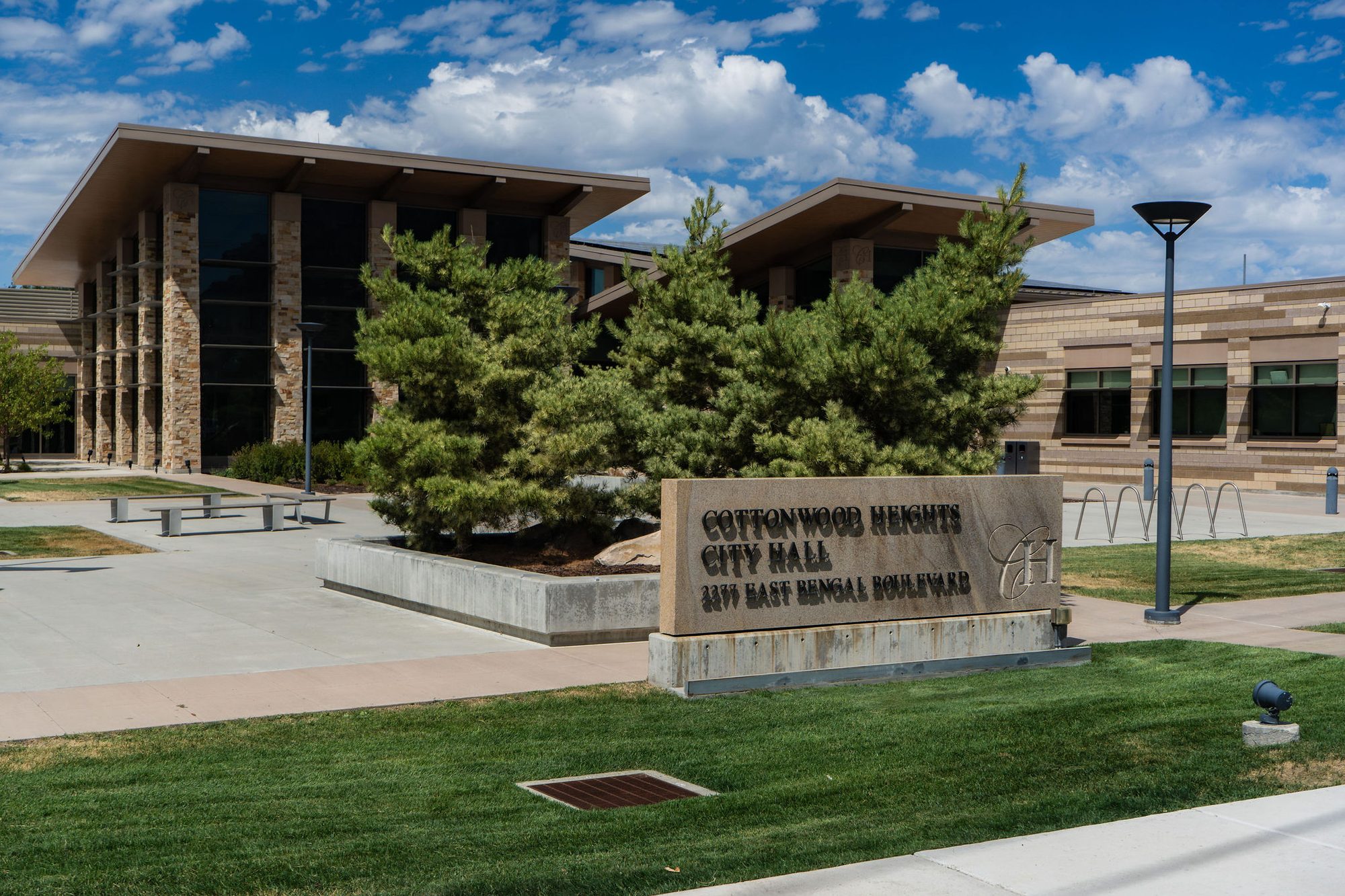 Modern stone and glass municipal building with landscaped plaza and monument sign.