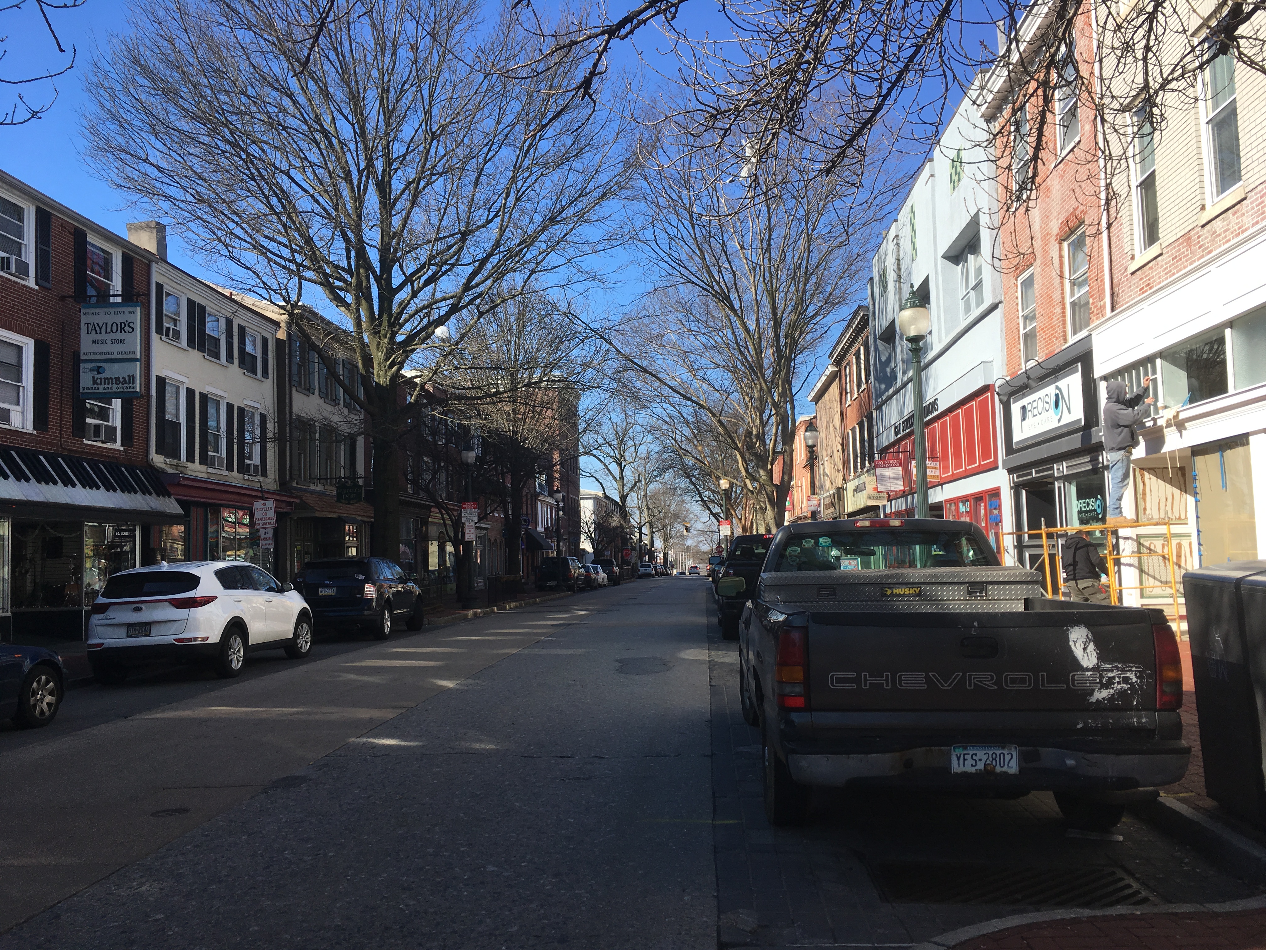 Westbound view of Gay Street lined with brick storefronts and bare street trees.