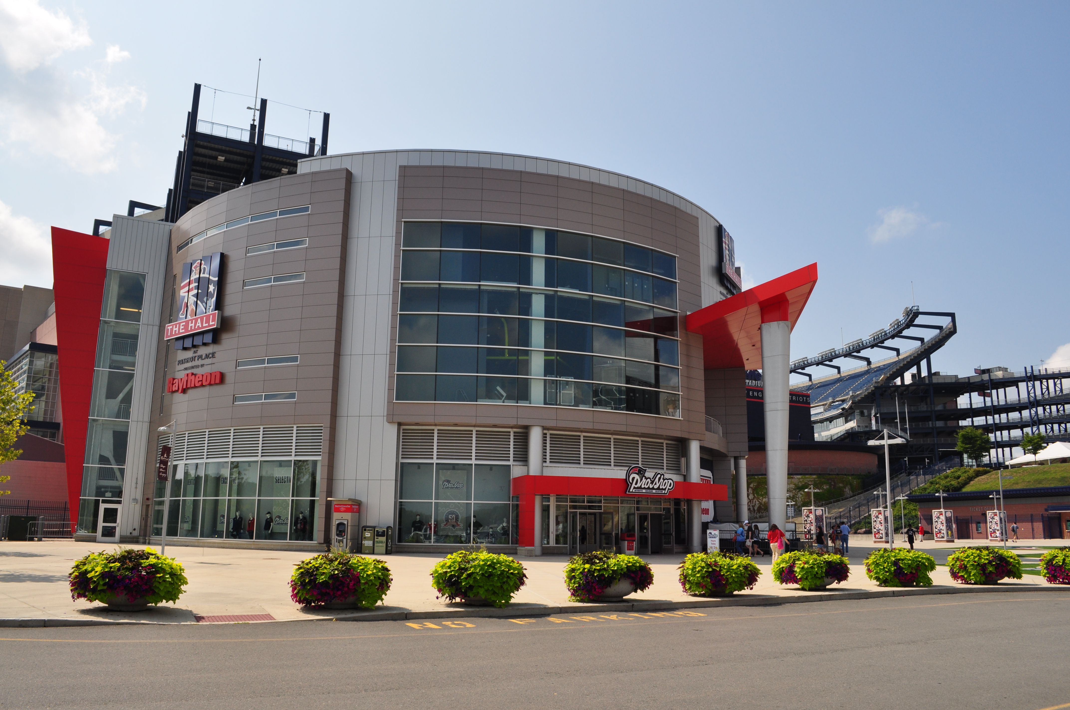 Curved modern stadium building exterior with large glass windows and red architectural accents.