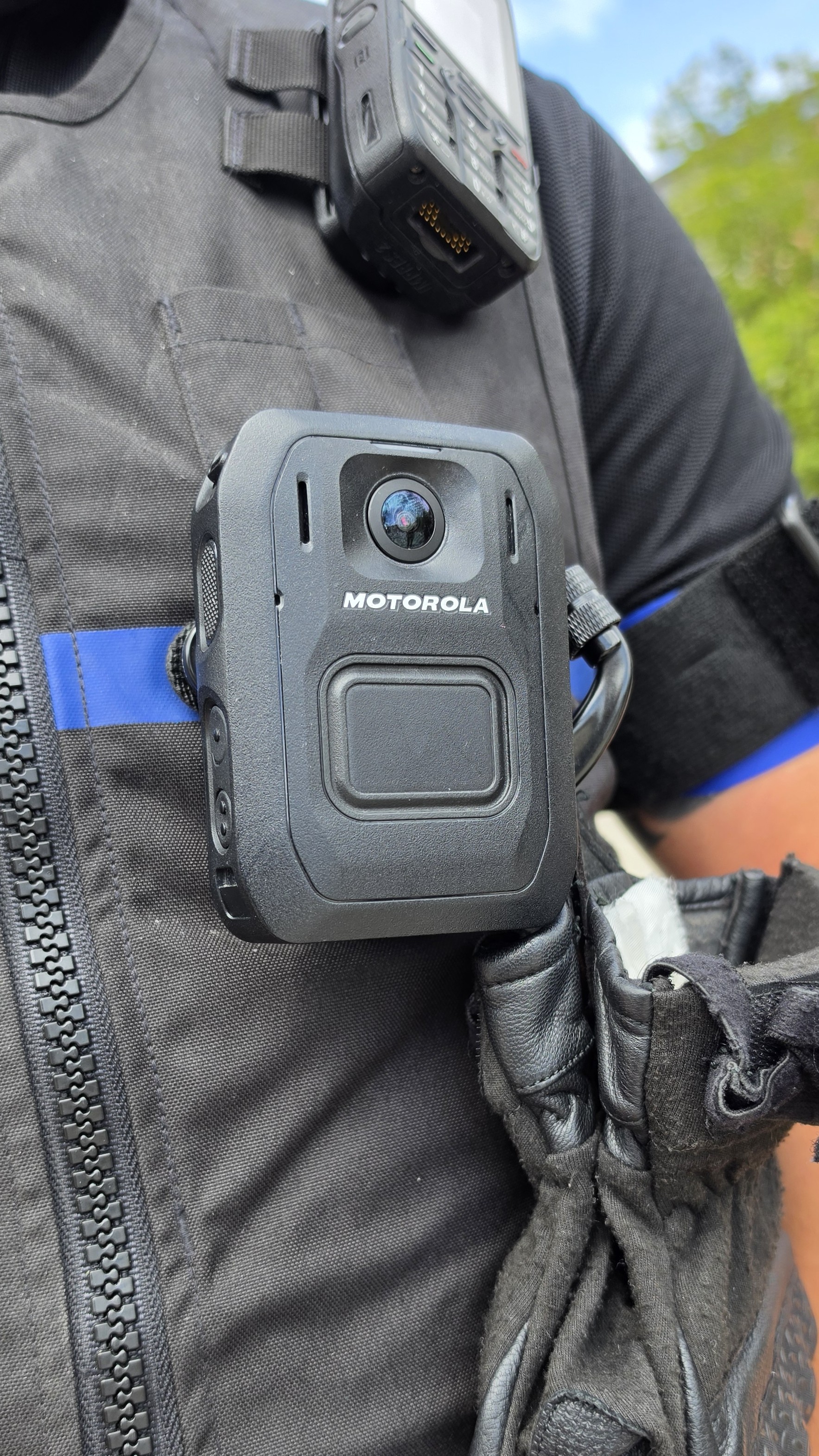 A Motorola body camera clipped to the chest of a black tactical vest.