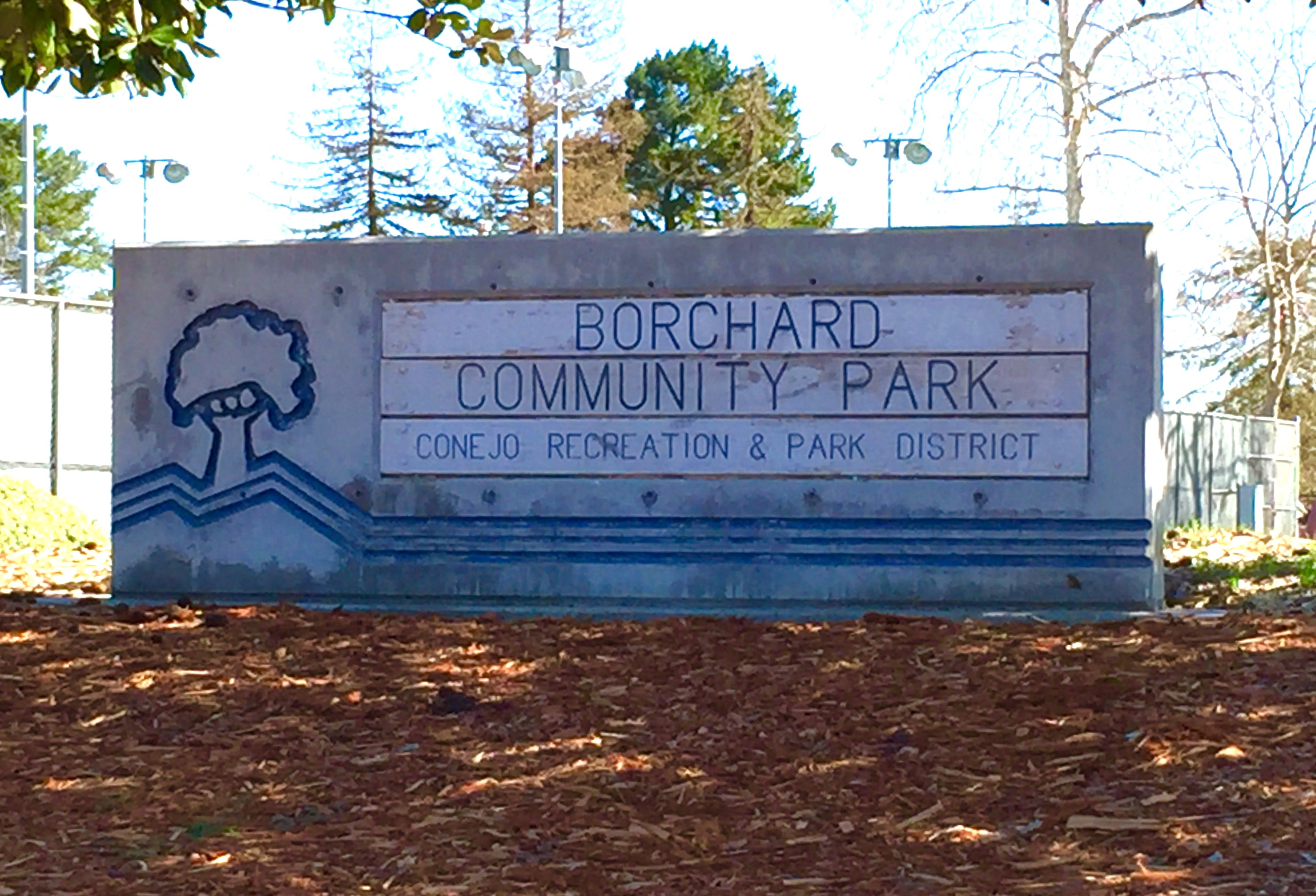 Concrete entrance sign reading Borchard Community Park surrounded by trees.