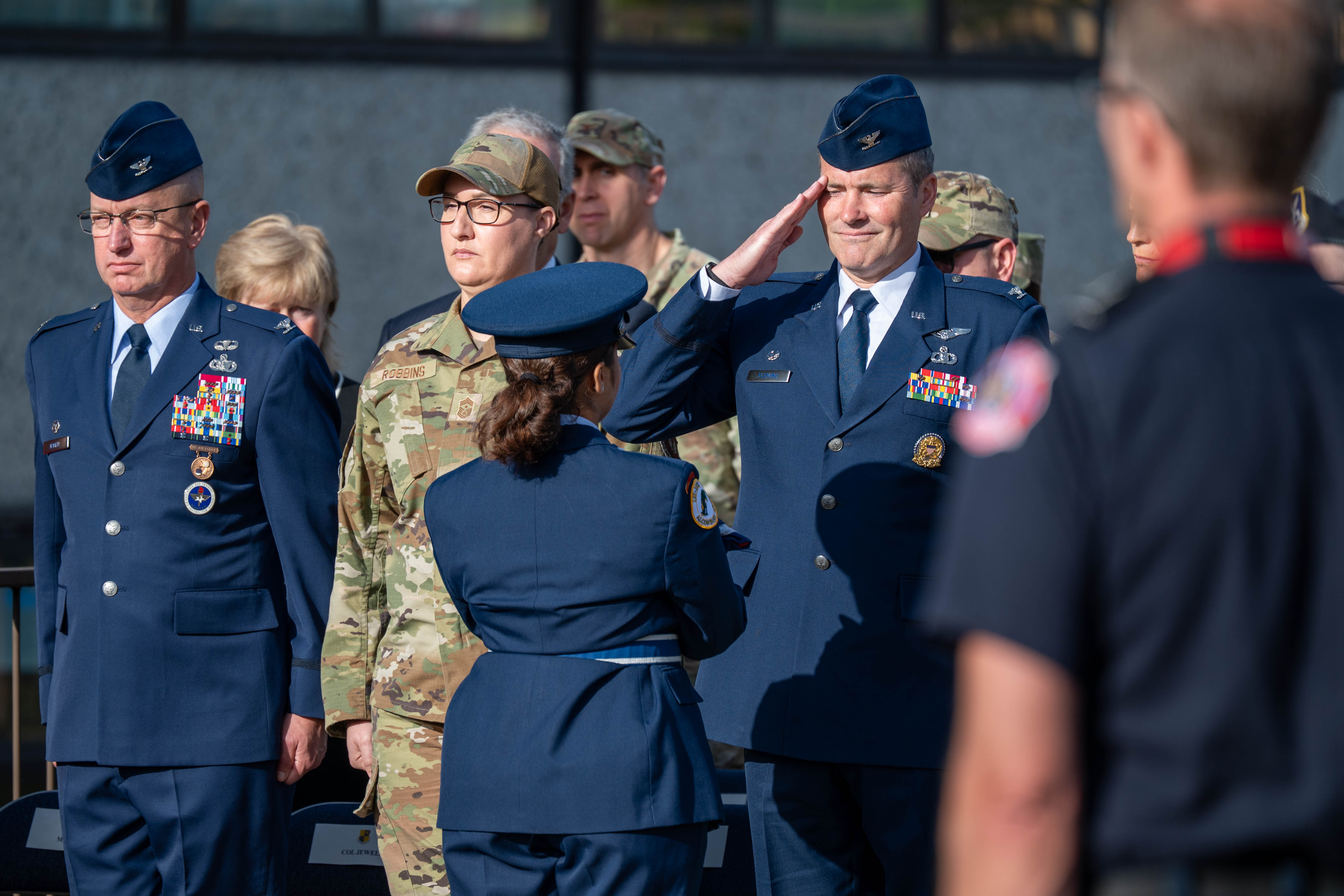 Military officers in dress uniforms stand at a formal 9/11 memorial ceremony.