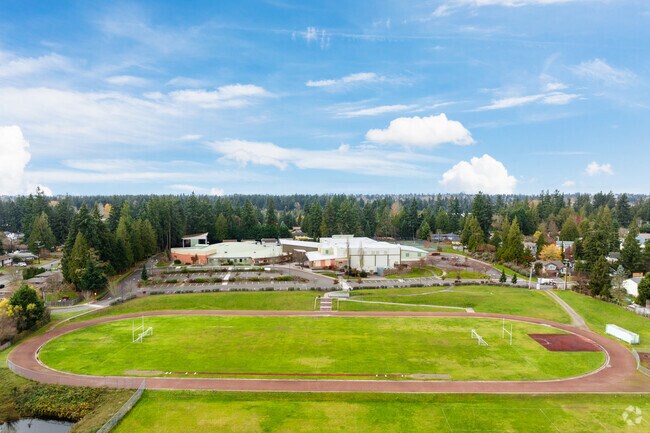 Aerial view of a middle school campus with a red running track and evergreen trees.