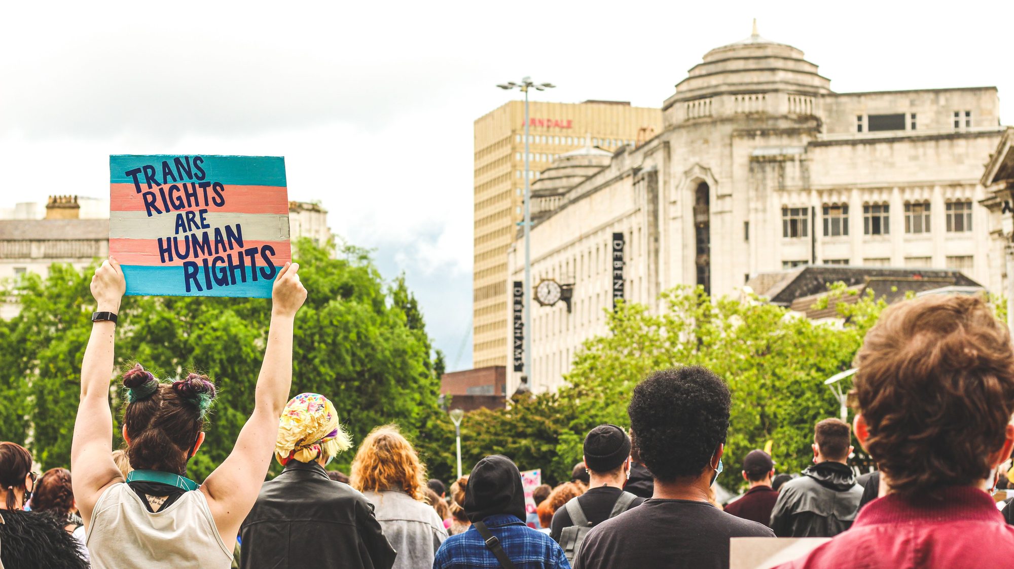 A peaceful LGBTQ protest with a focus on transgender rights in a city setting.