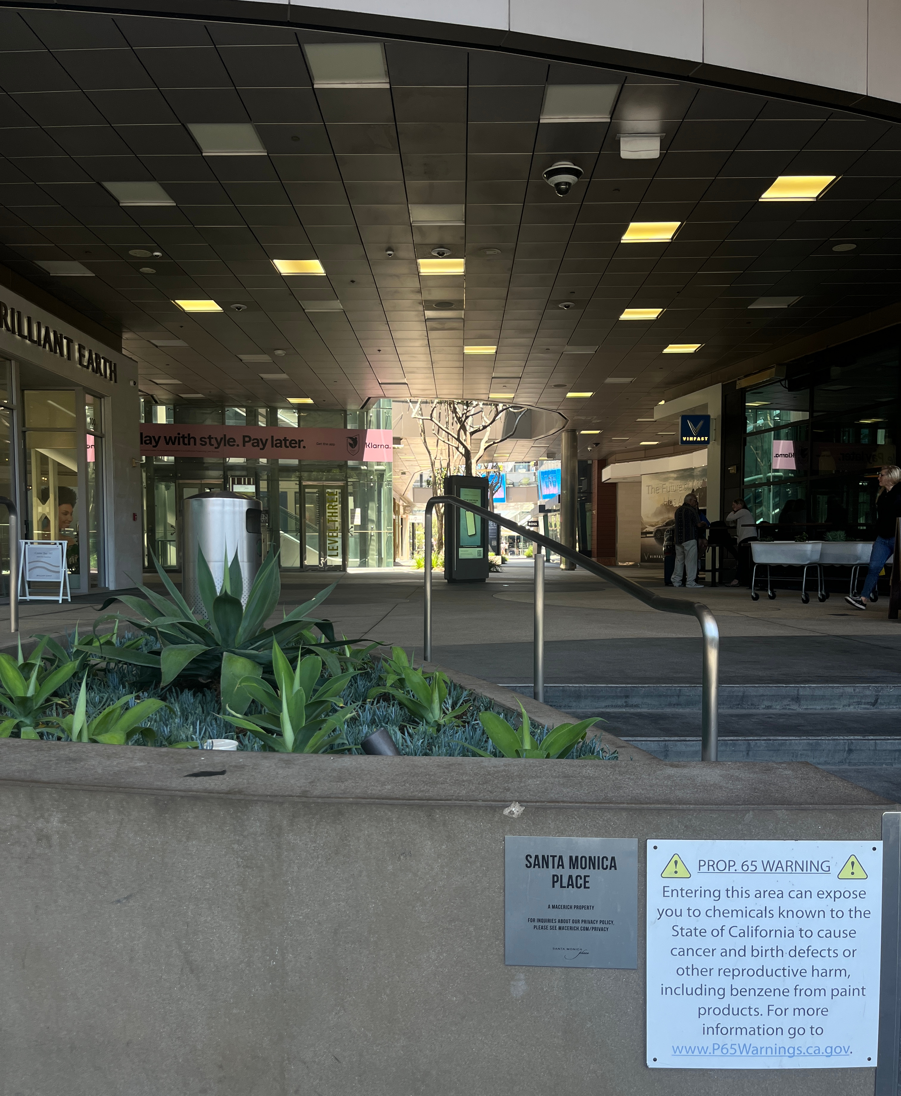 Covered mall entrance with succulent planters, recessed lighting, and a Santa Monica Place sign.