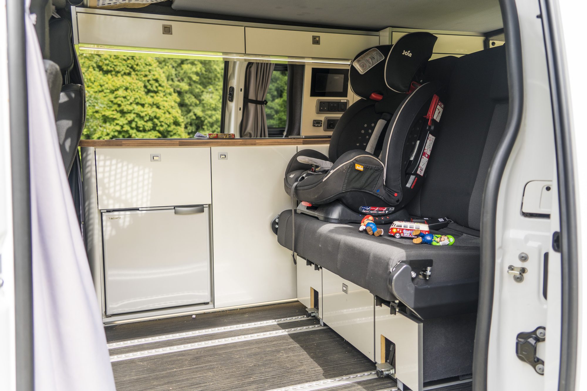 Photograph of a child's car seat in the back of a camper van about to embark on a road trip.  Children's toys are located next to the car seat.
Please use this image and provide a link back to https://www.cruiseamerica.com