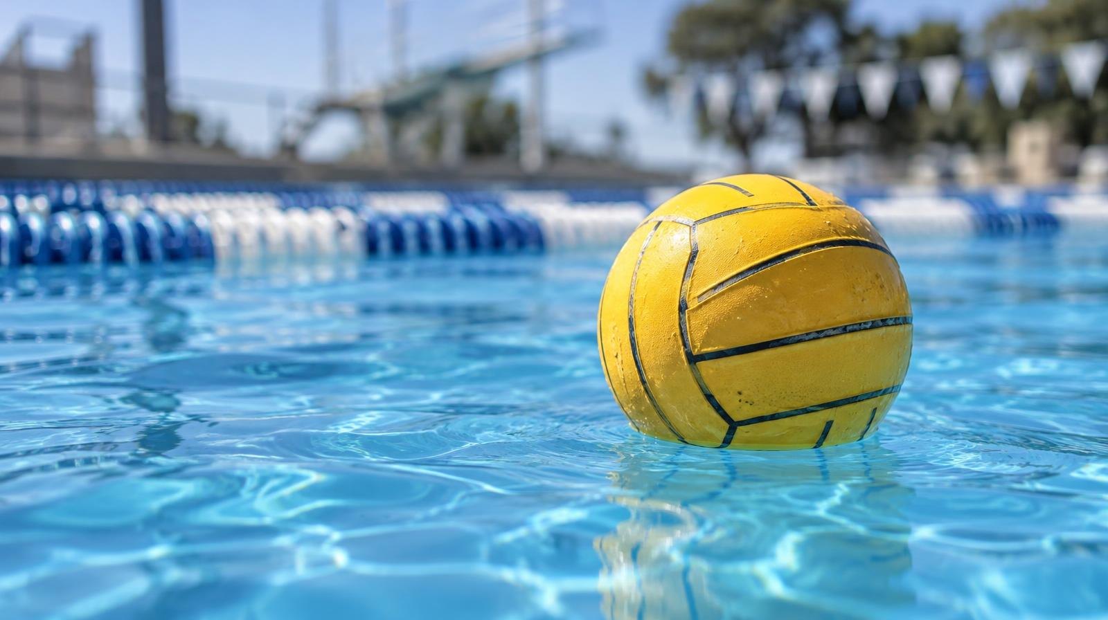 A water polo ball resting on the surface of a blue pool.