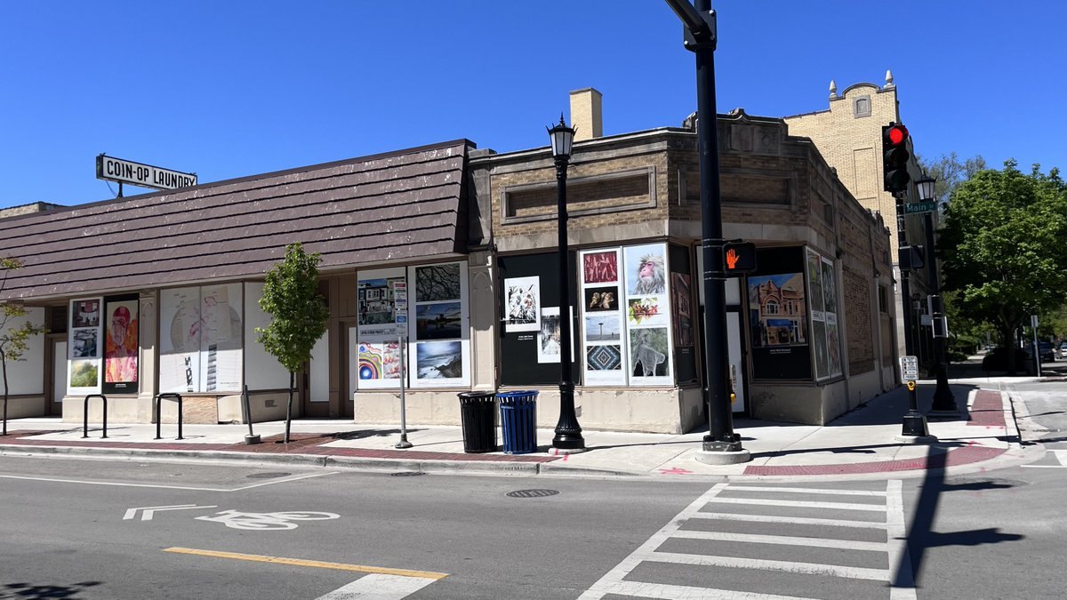 A vacant corner commercial building with artwork in the windows at a street intersection.