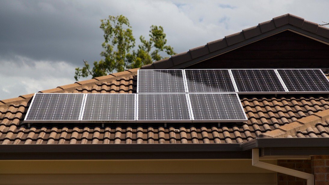 Solar panels mounted on a red clay tile roof of a residential home.