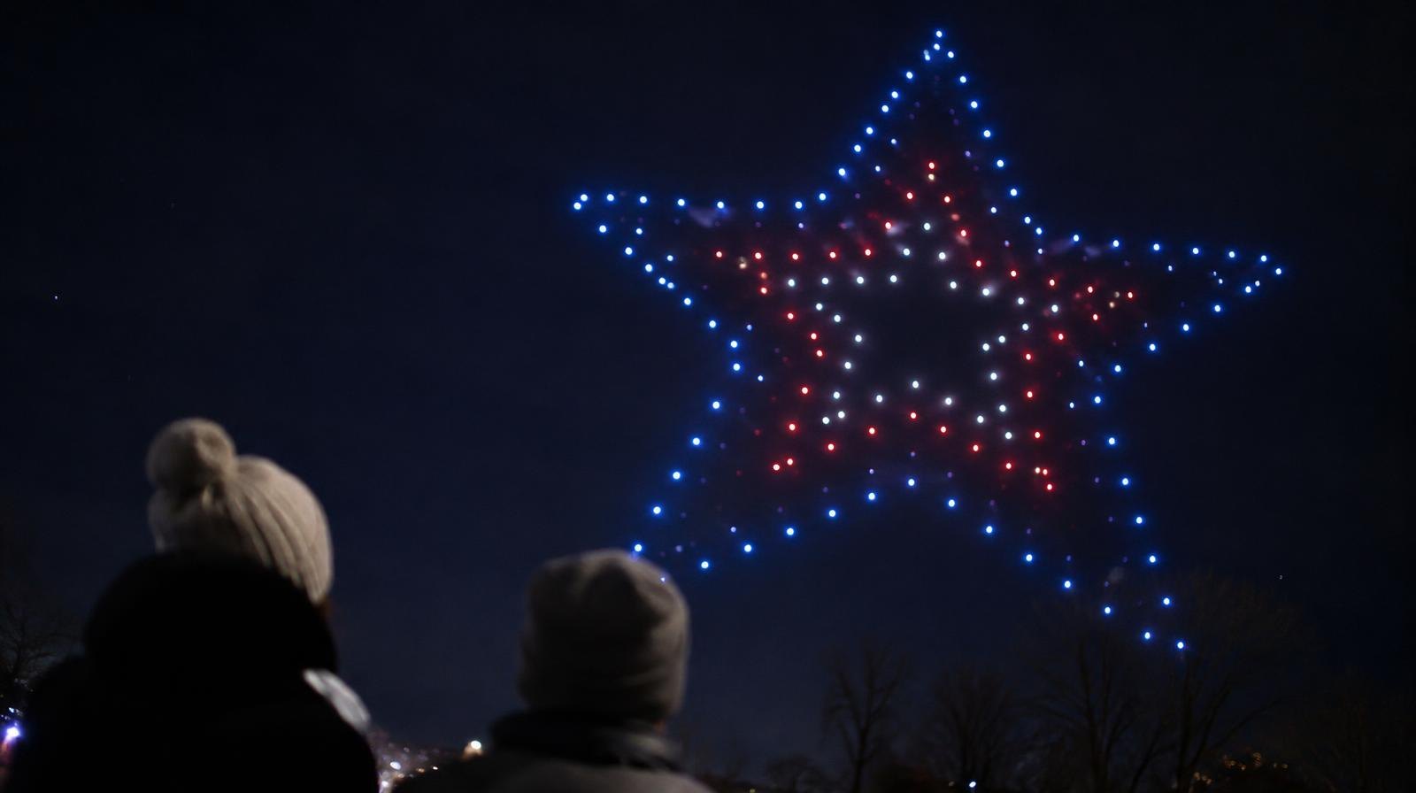 Glowing drones arranged in a formation against a dark night sky.